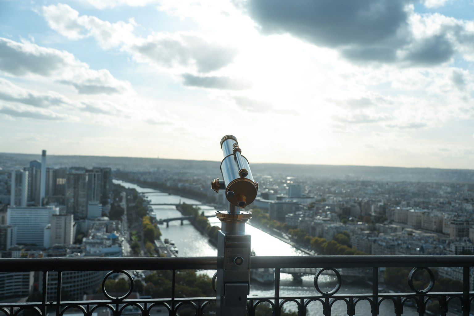Telescopio en una plataforma de observación alta con vista a un río y el paisaje urbano