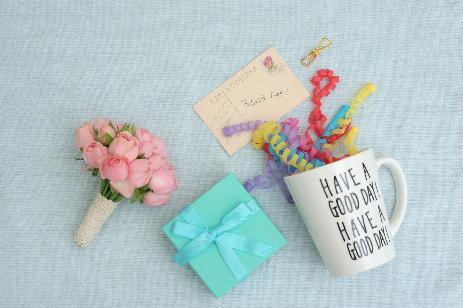 A table arrangement with a bouquet, a gift box, a mug, and a message card