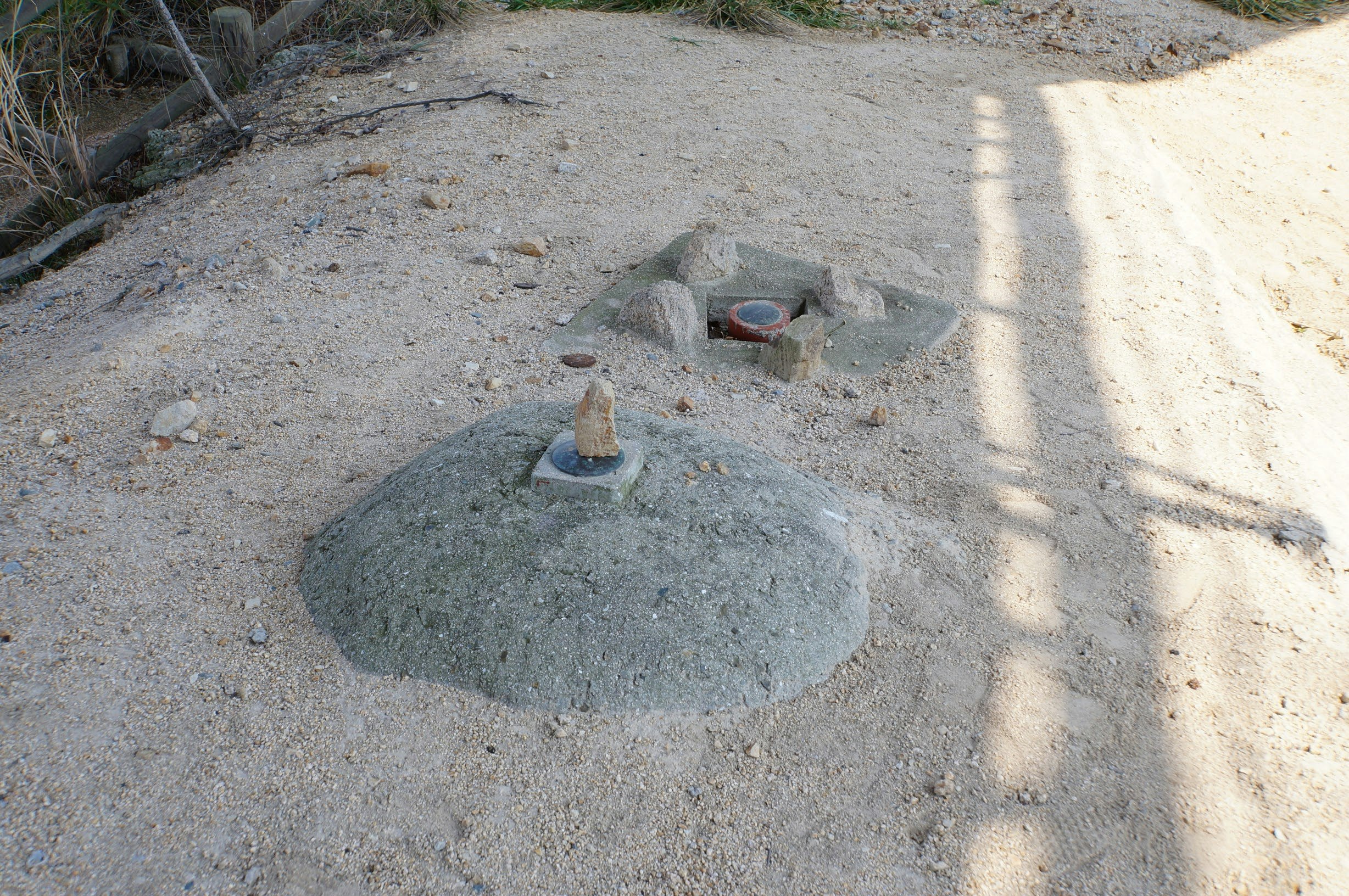 砂地に置かれた小さな石の水飲み場と影