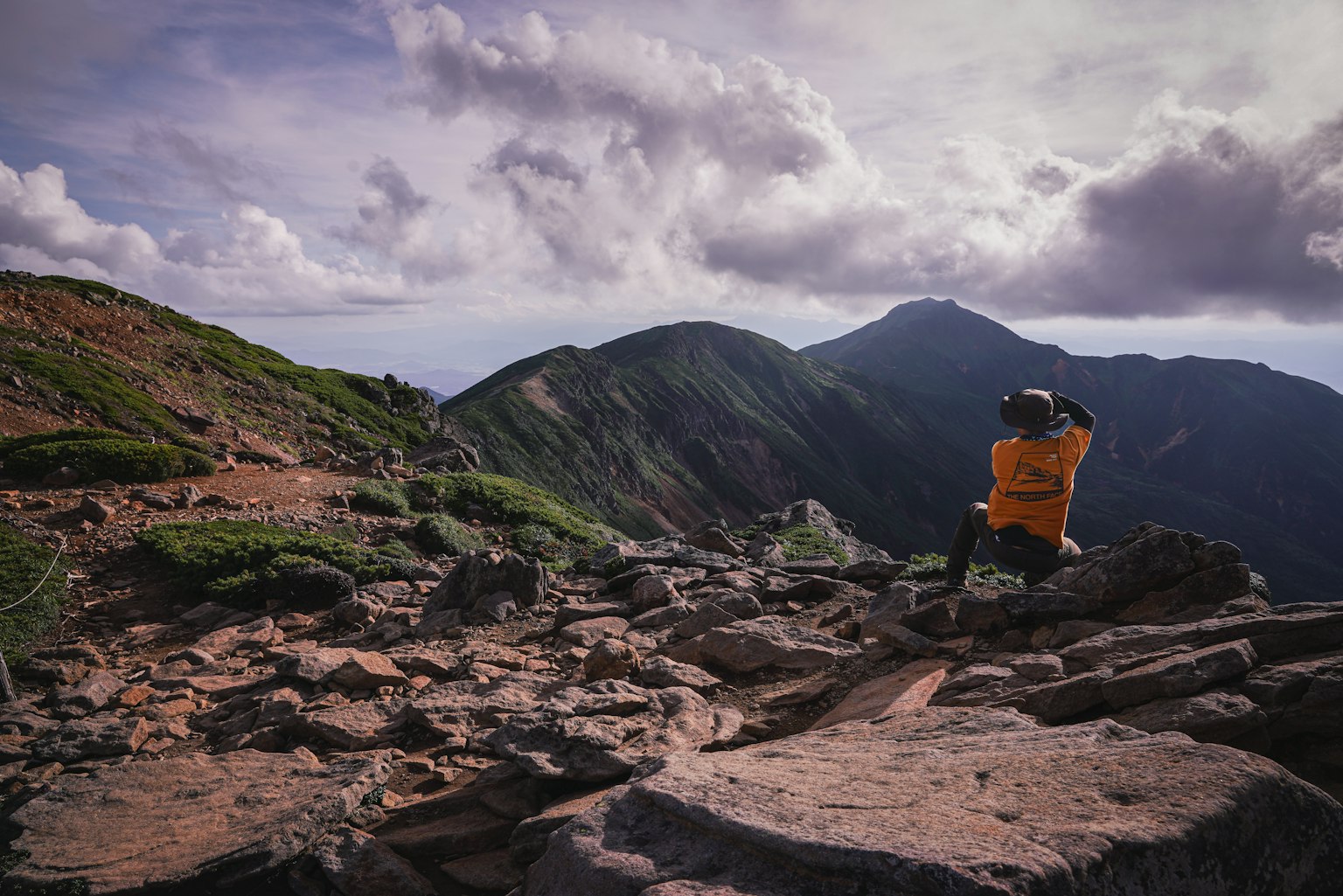 Pendaki duduk di atas batu dengan latar belakang pegunungan