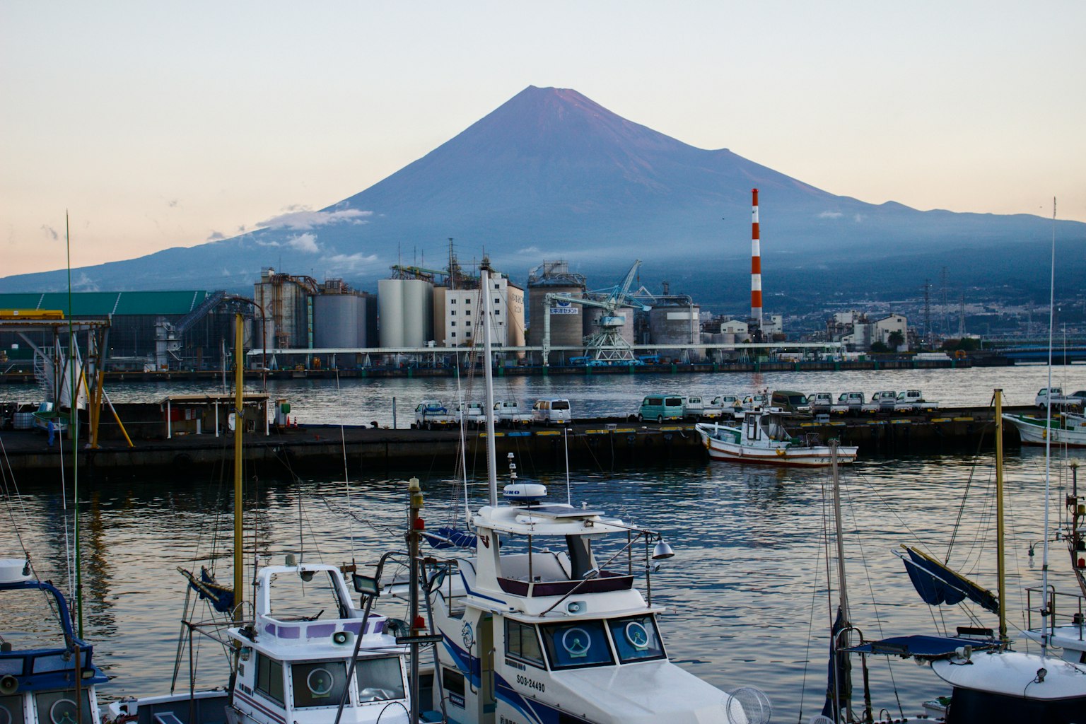 Vista del porto con il monte Fuji sullo sfondo barche e fabbriche allineate