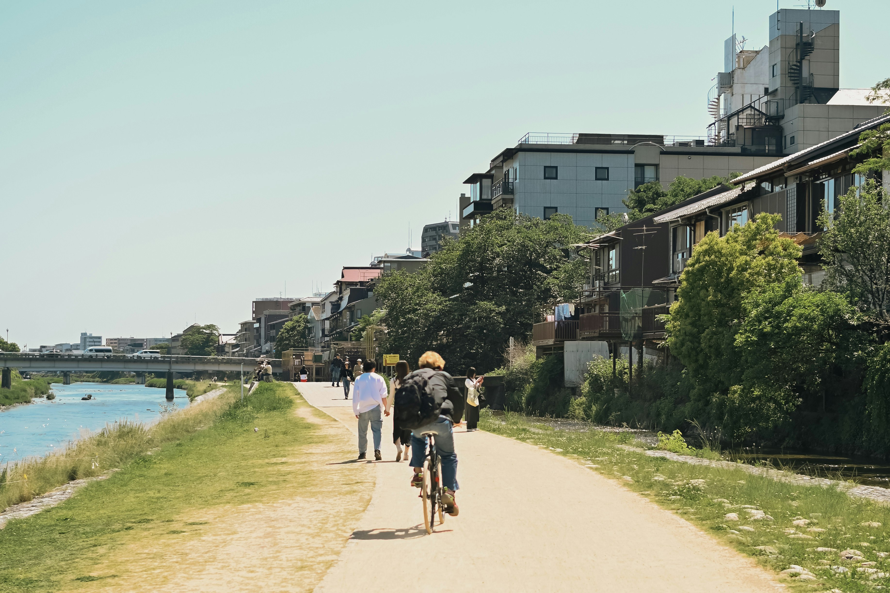 people and bicycles walking along a riverside promenade