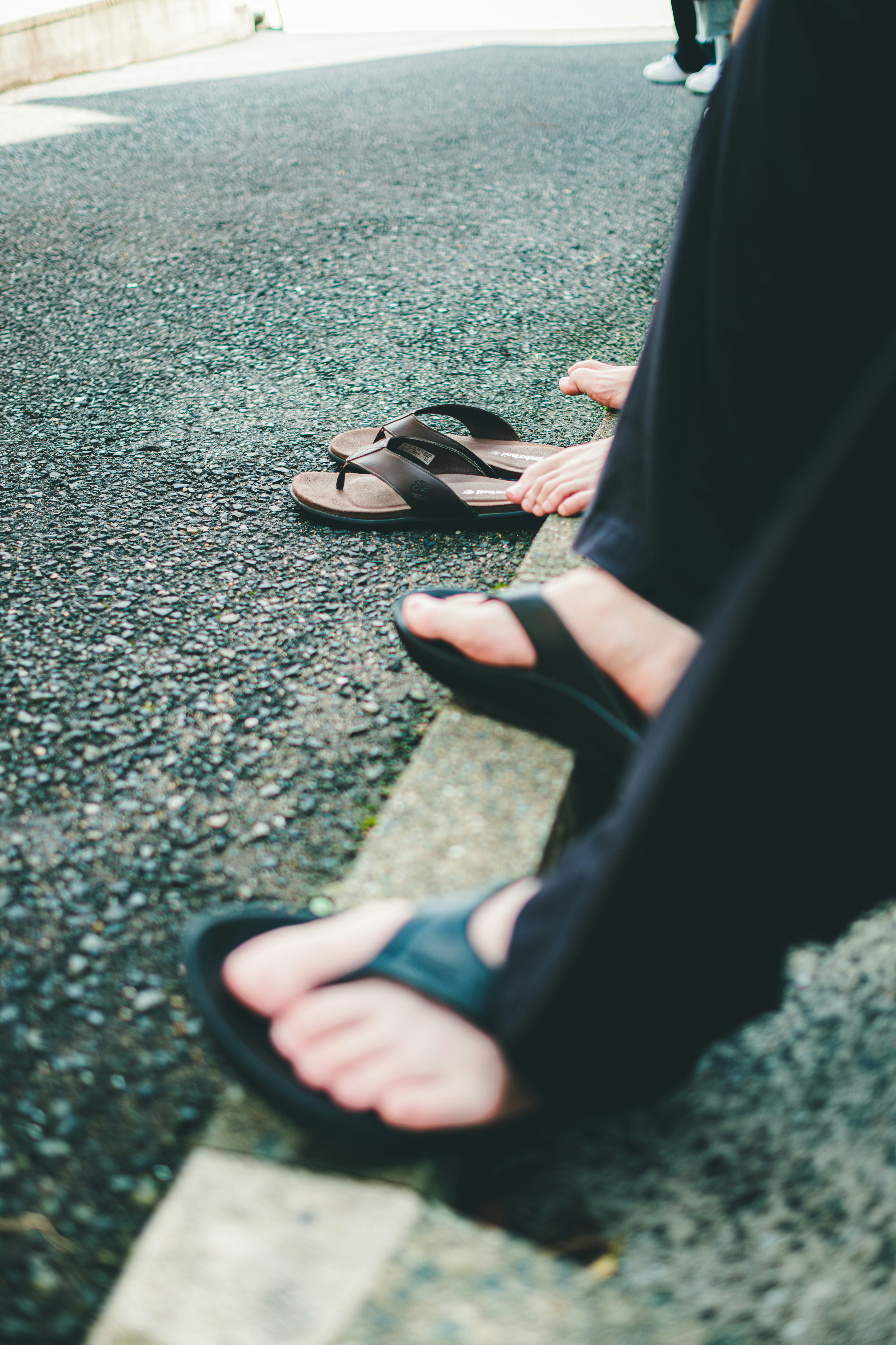 piedi di amici che si tolgono le sandali in una giornata estiva calda in strada