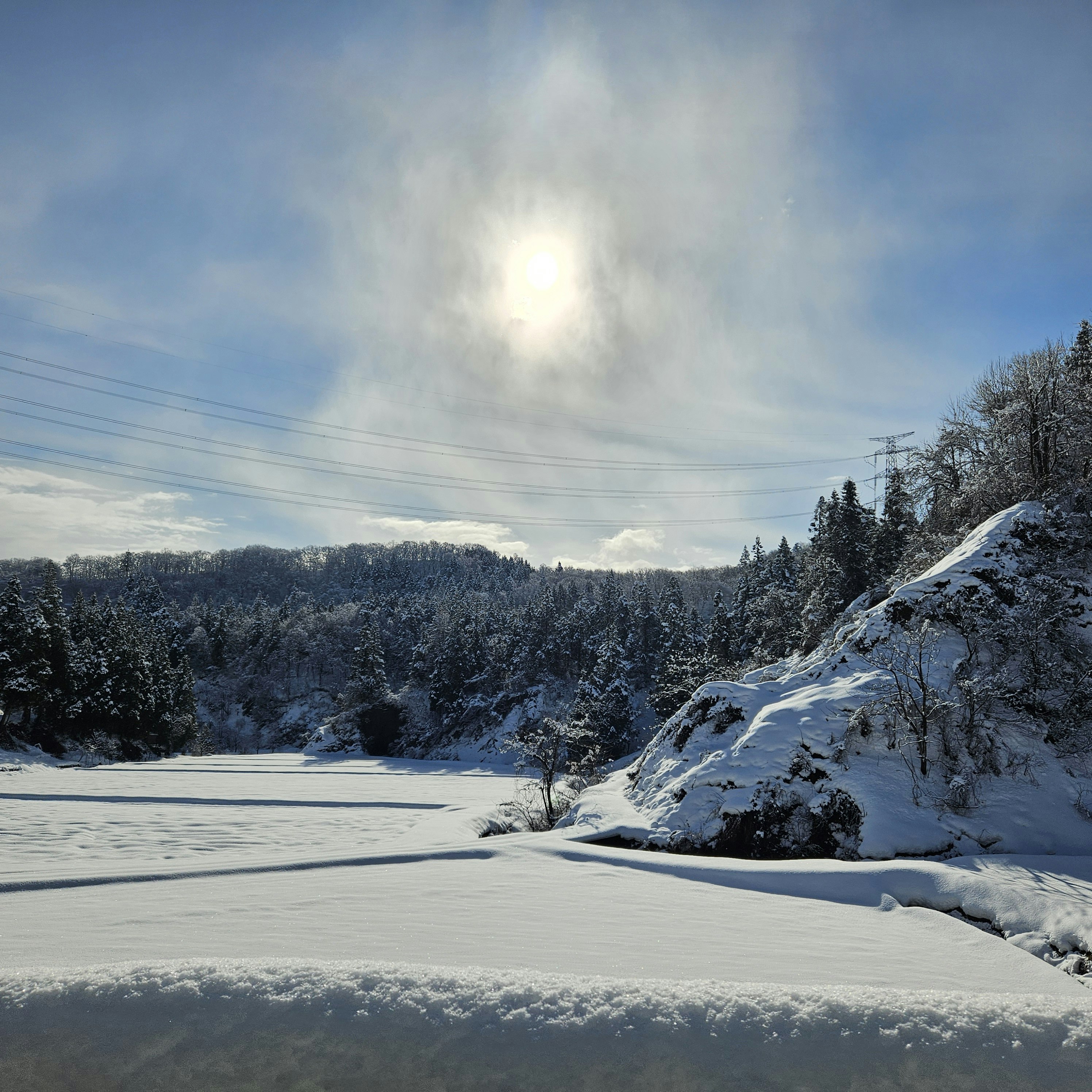 雪の積もる湖畔と雪山のある曇り空の風景