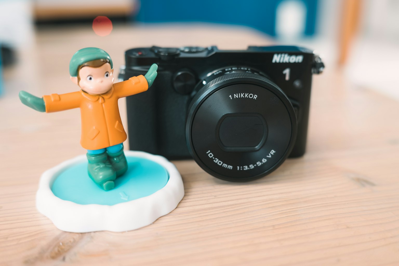 Một mô hình đứng bên cạnh máy ảnh Nikon trên bề mặt gỗ