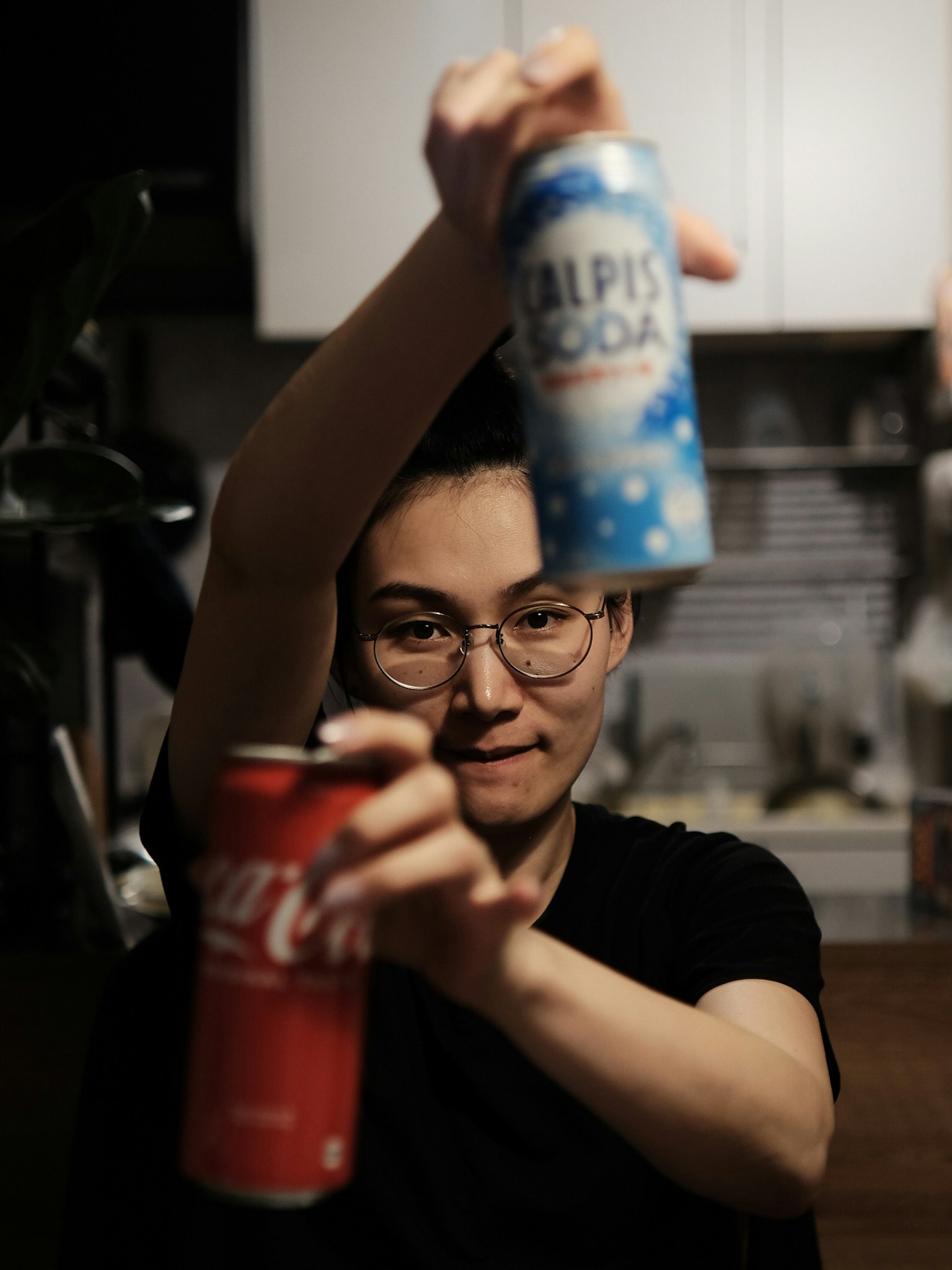 手持可口可樂和阿爾皮斯飲料罐的人