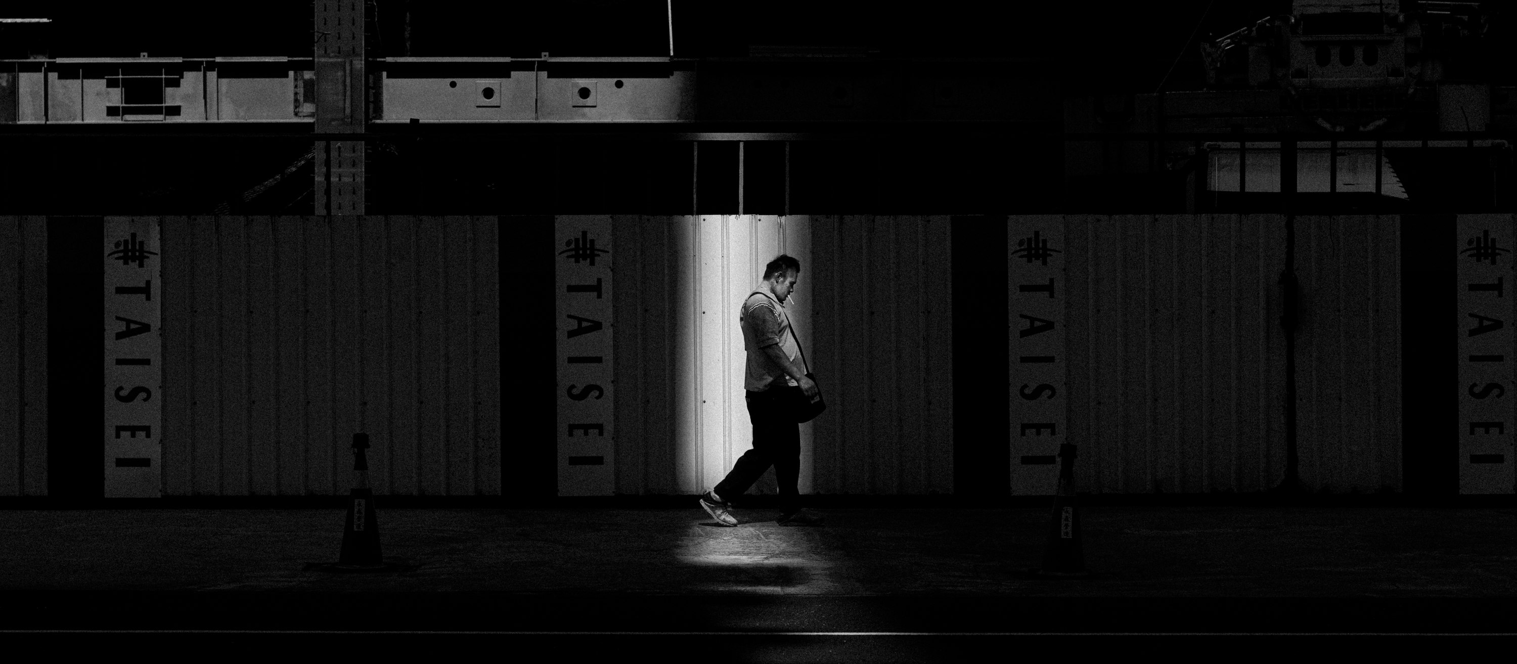 コンテナ倉庫の通路を歩く人物のシルエット