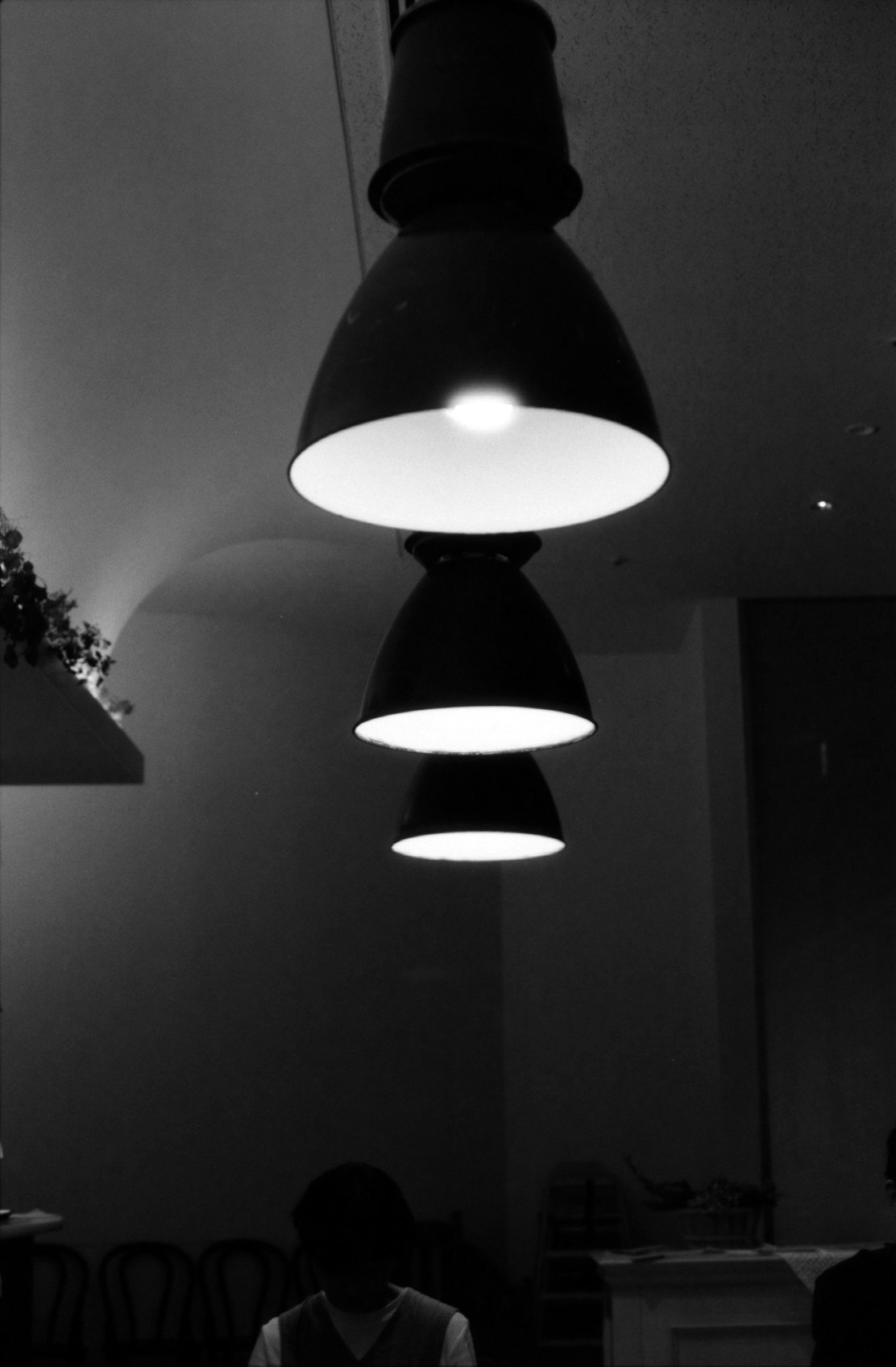 spazio espositivo monocromatico con lampade sospese e giochi di luce e ombra