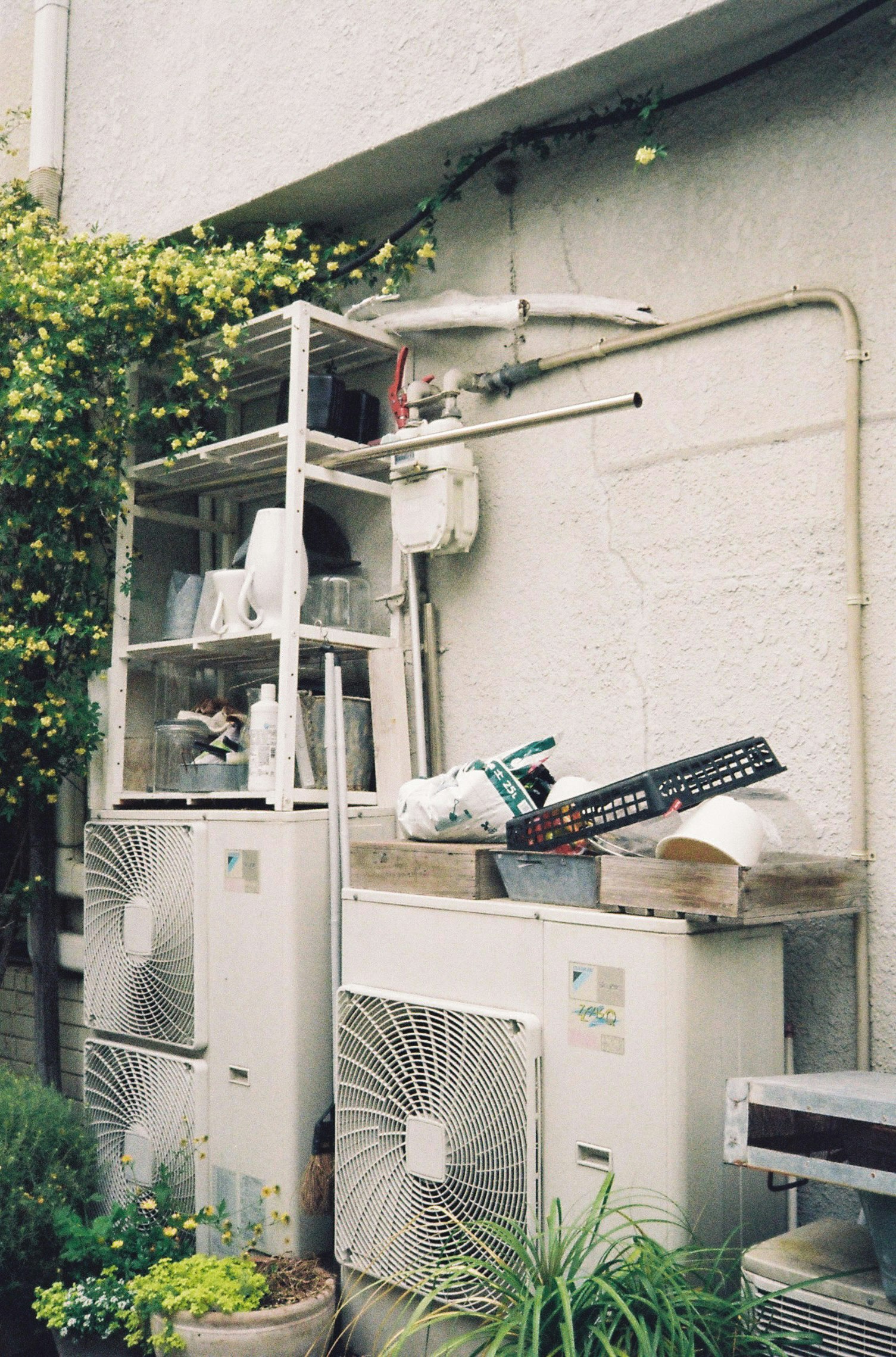 路地の壁際に置かれた屋外の空調機器と配管