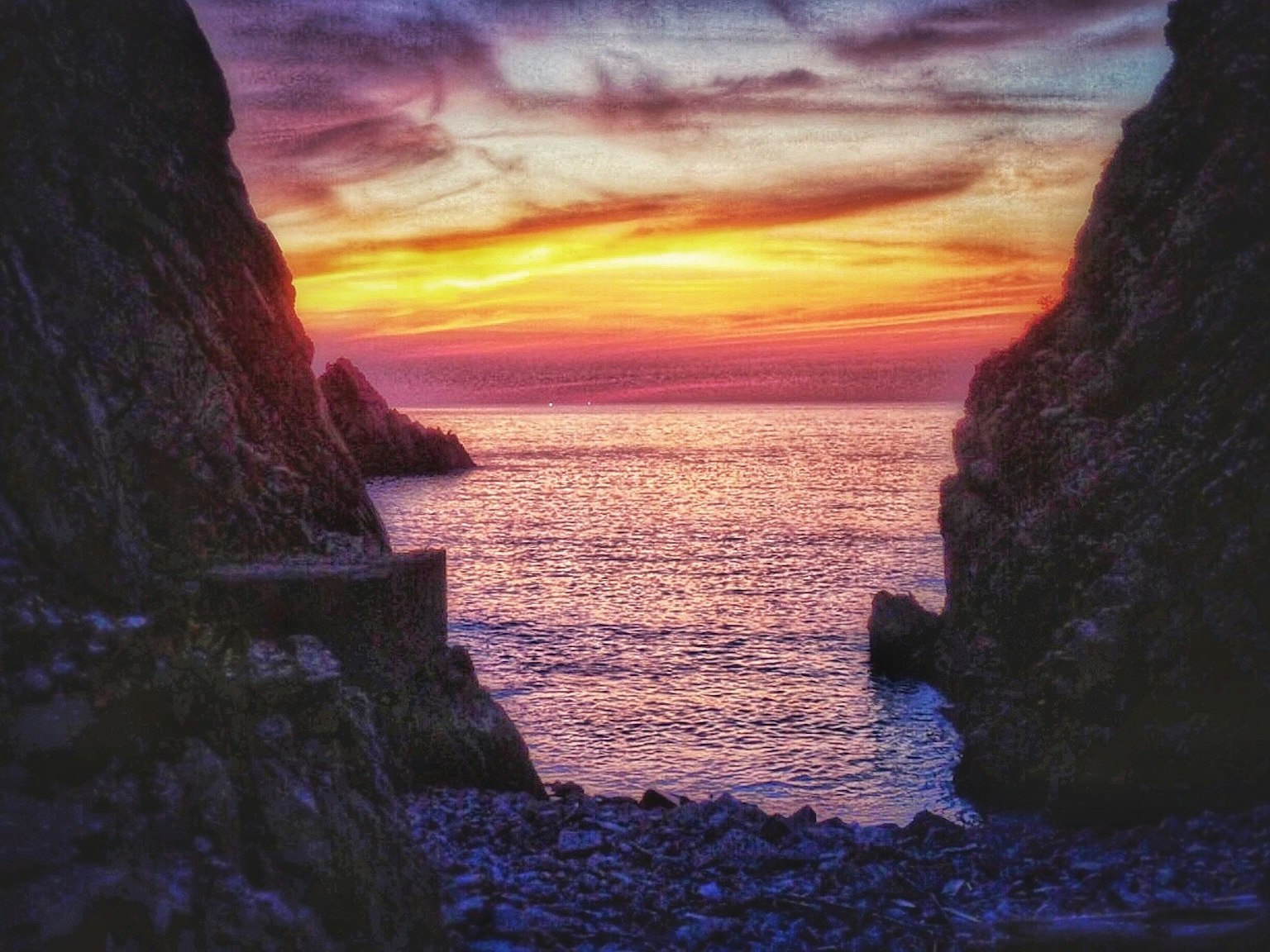 Coucher de soleil sur l'océan entouré de falaises rocheuses