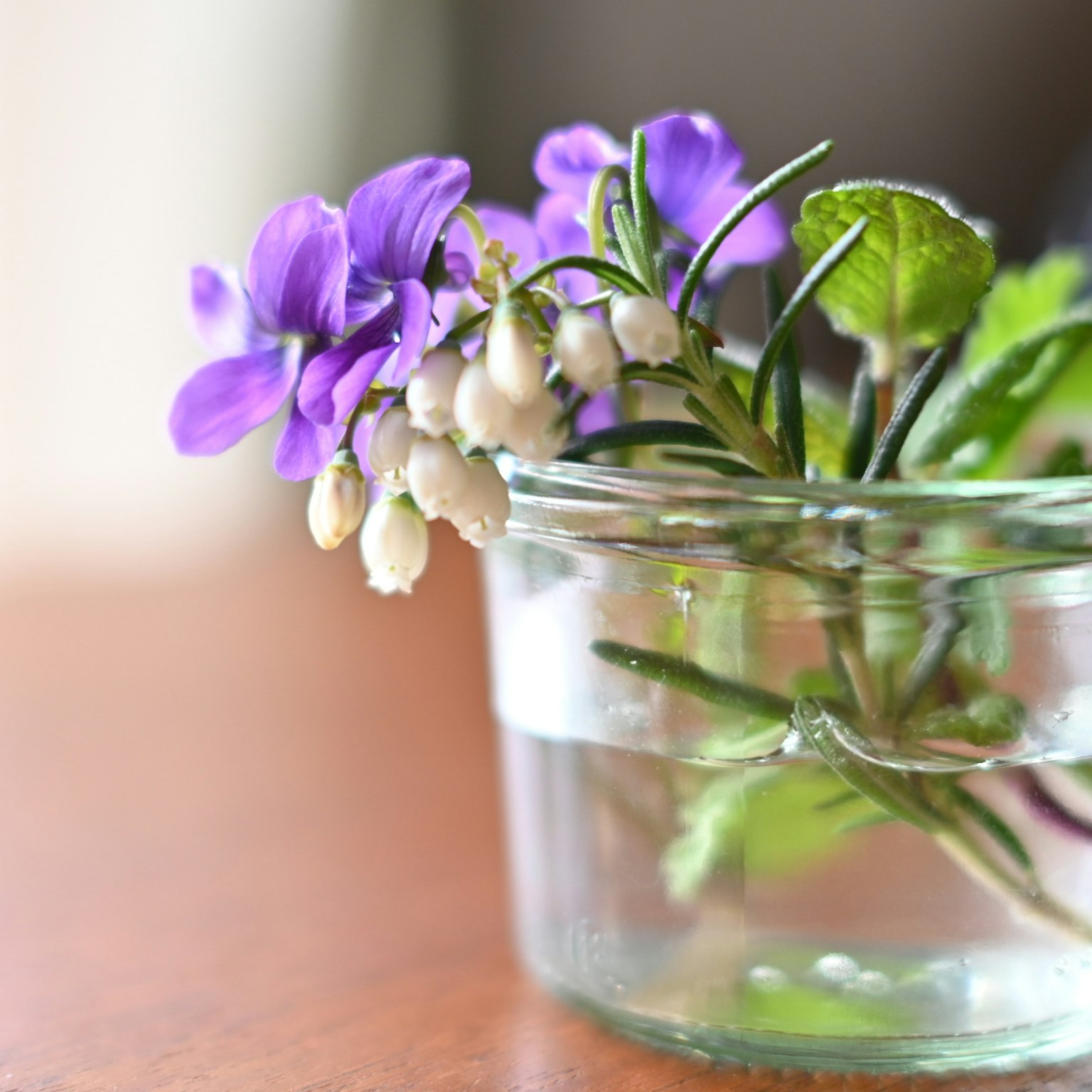 Un bouquet di fiori viola e bianchi in un vaso di vetro trasparente