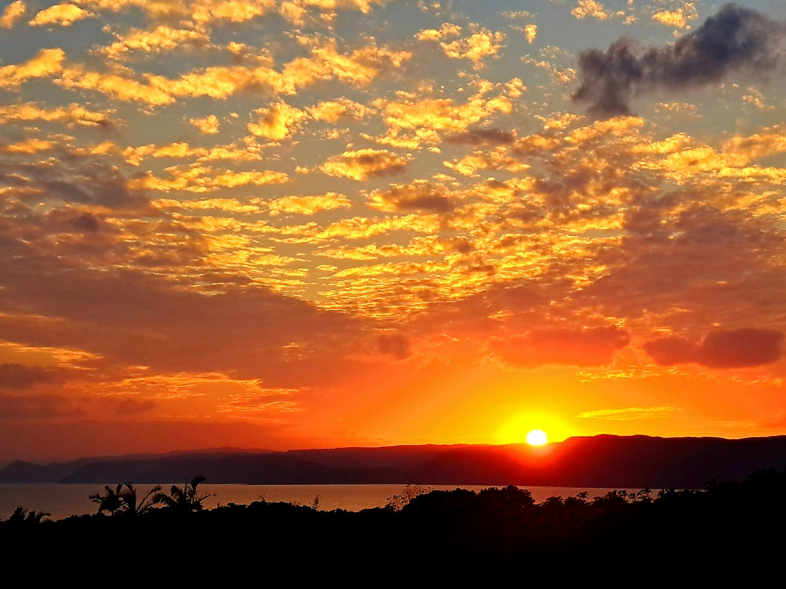 Hermoso atardecer sobre el océano con nubes naranjas y amarillas vibrantes
