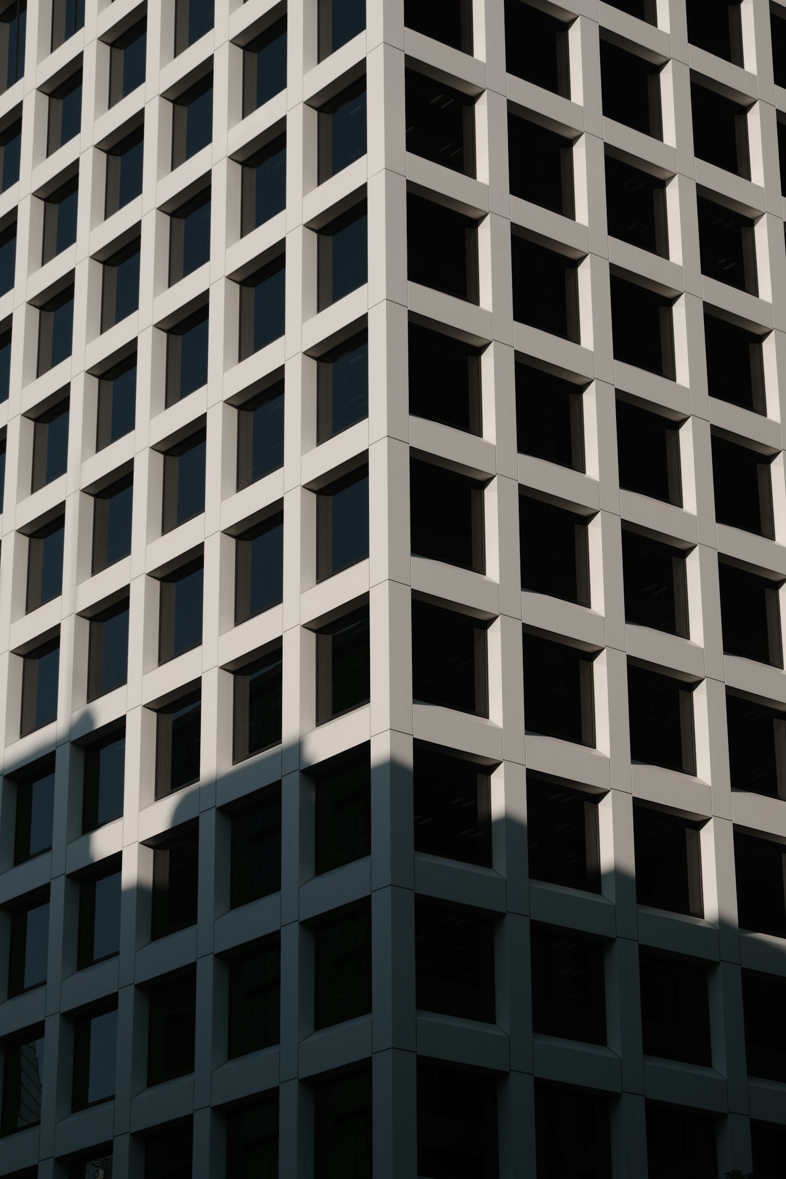 Gros plan d'un coin de bâtiment moderne avec façade blanche et fenêtres noires