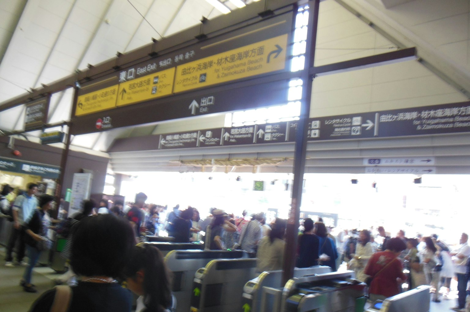 สถานีรถไฟที่มีผู้คนหนาแน่นพร้อมประตูและป้ายทิศทาง
