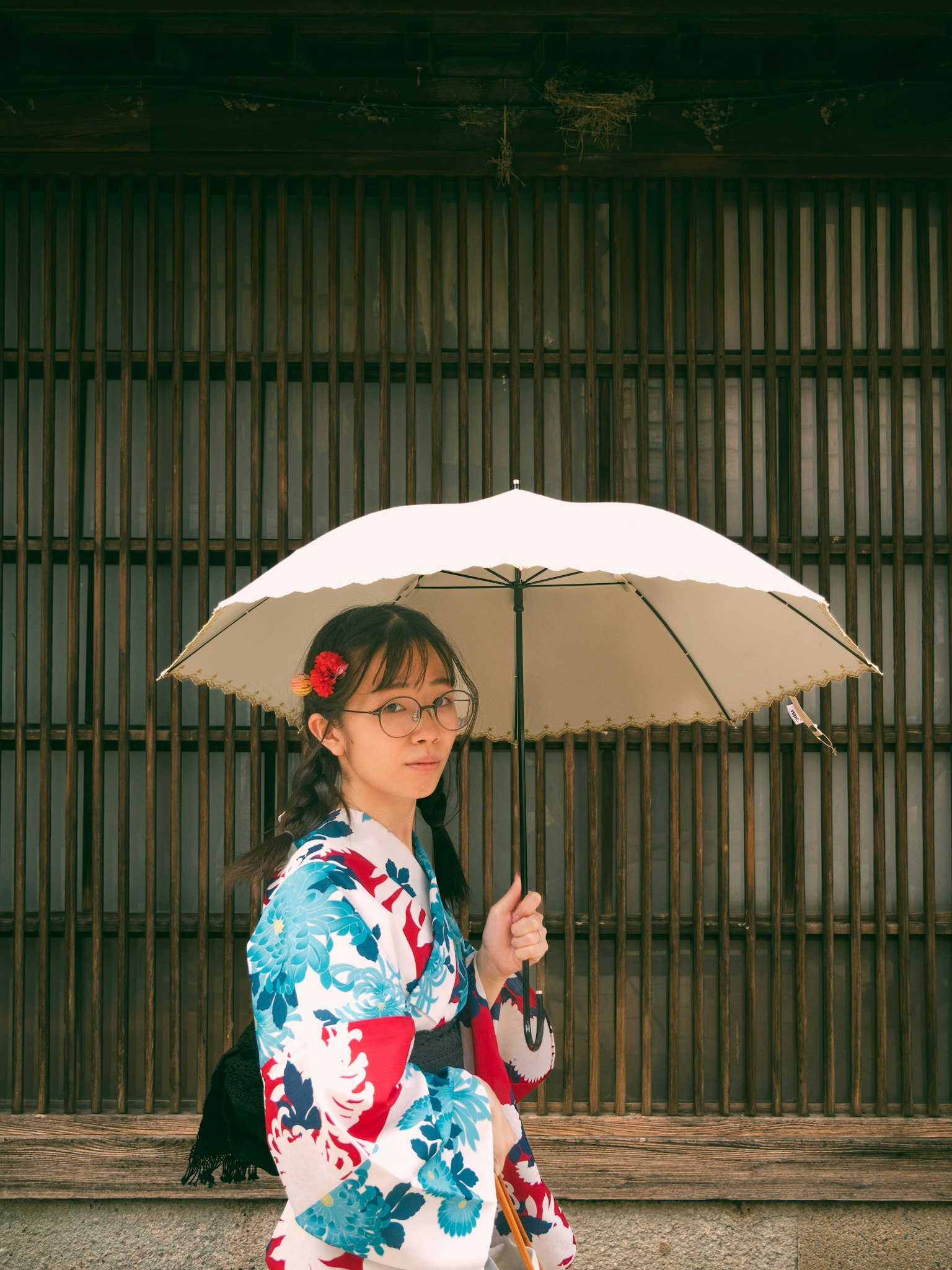 A woman in a kimono holding an umbrella in a street setting