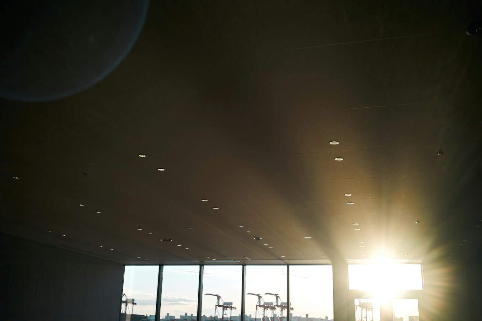 Innenansicht mit Sonnenlicht, das durch große Fenster strömt, und Deckenlichtern