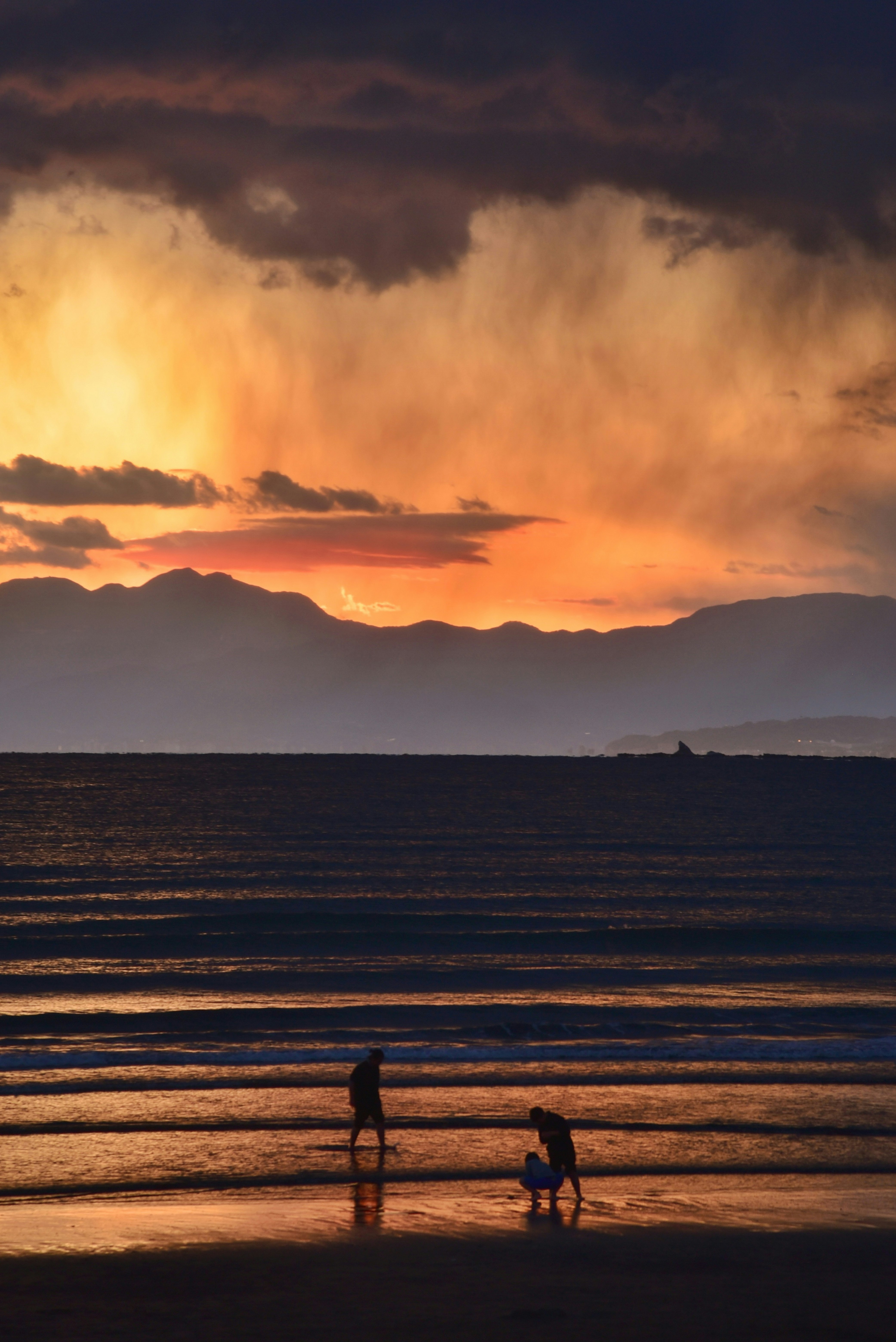 夕焼けの海岸で二人の人が波打ち際で遊んでいる美しい風景