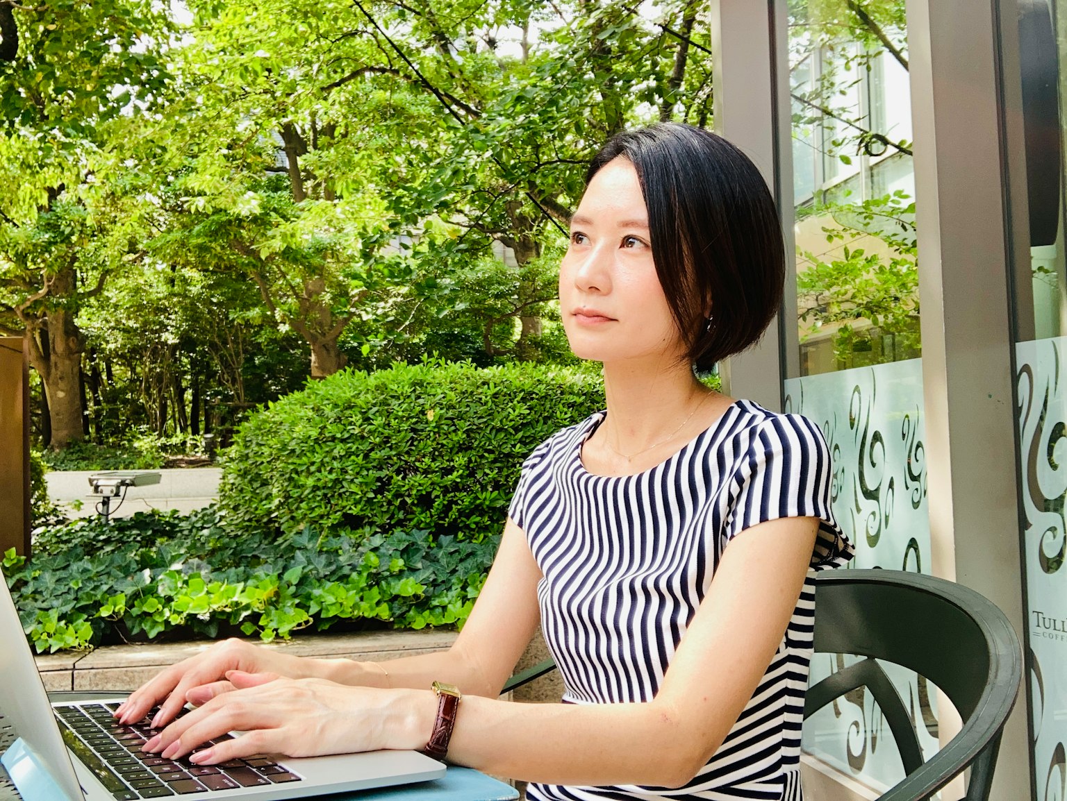 在郁郁蔥蔥的公園中使用筆記型電腦的女性