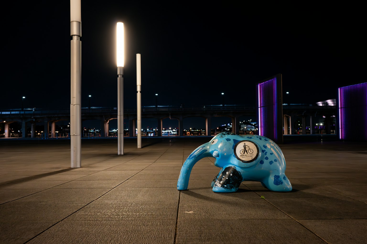 Scultura di elefante blu con orologio in un contesto urbano notturno