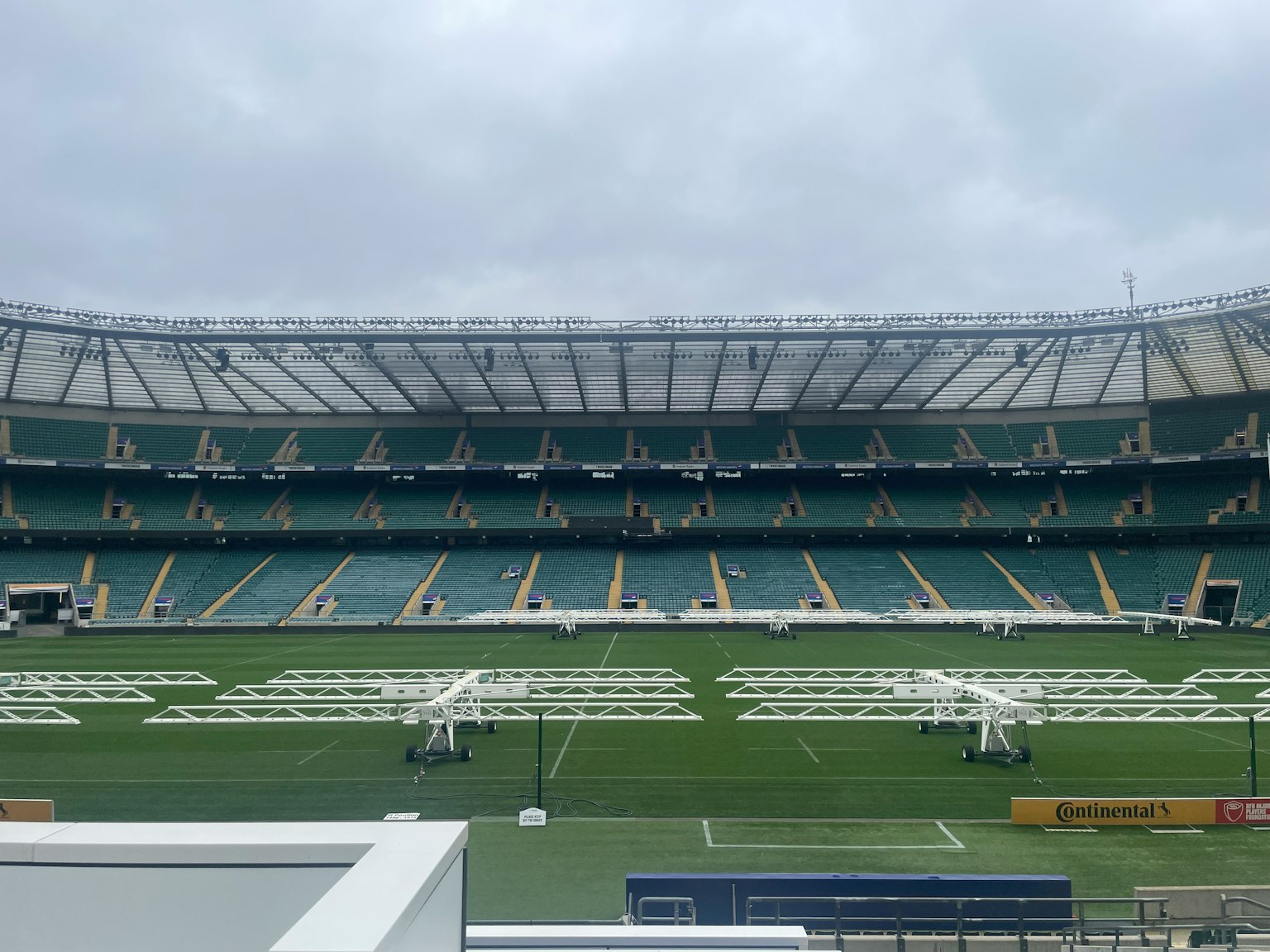 Interno di uno stadio vuoto con campo verde e file di seggiolini
