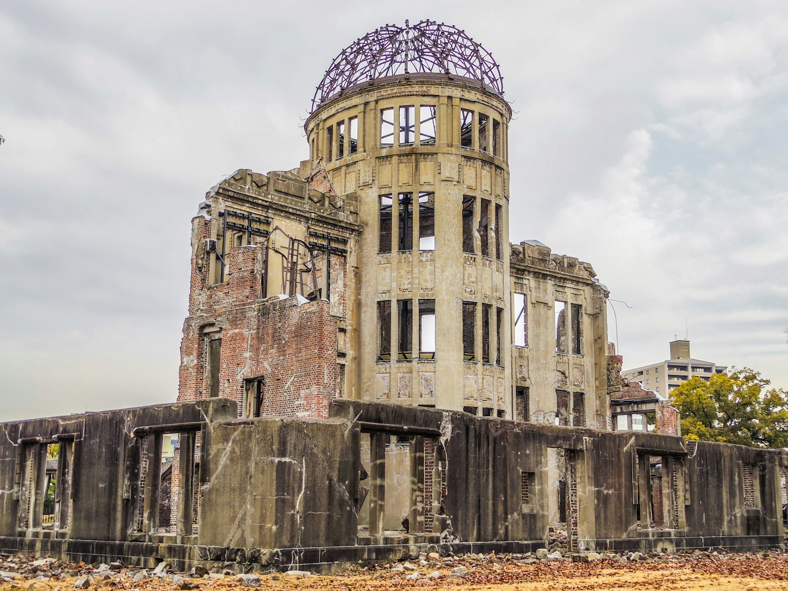 Image des ruines du Dôme de la bombe atomique avec un ciel gris et une végétation environnante