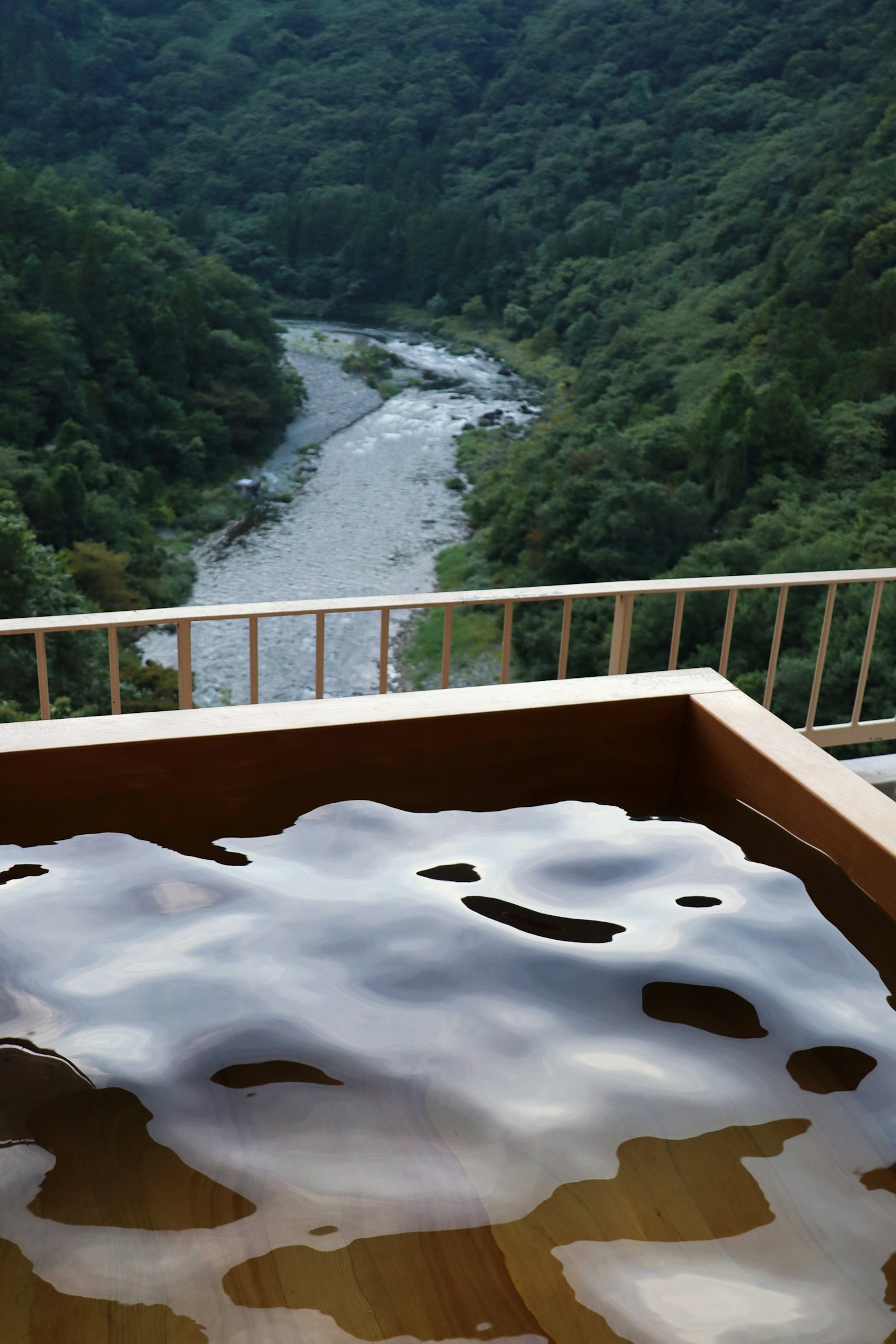 Vista escénica desde un manantial al aire libre con vista a un río y montañas verdes
