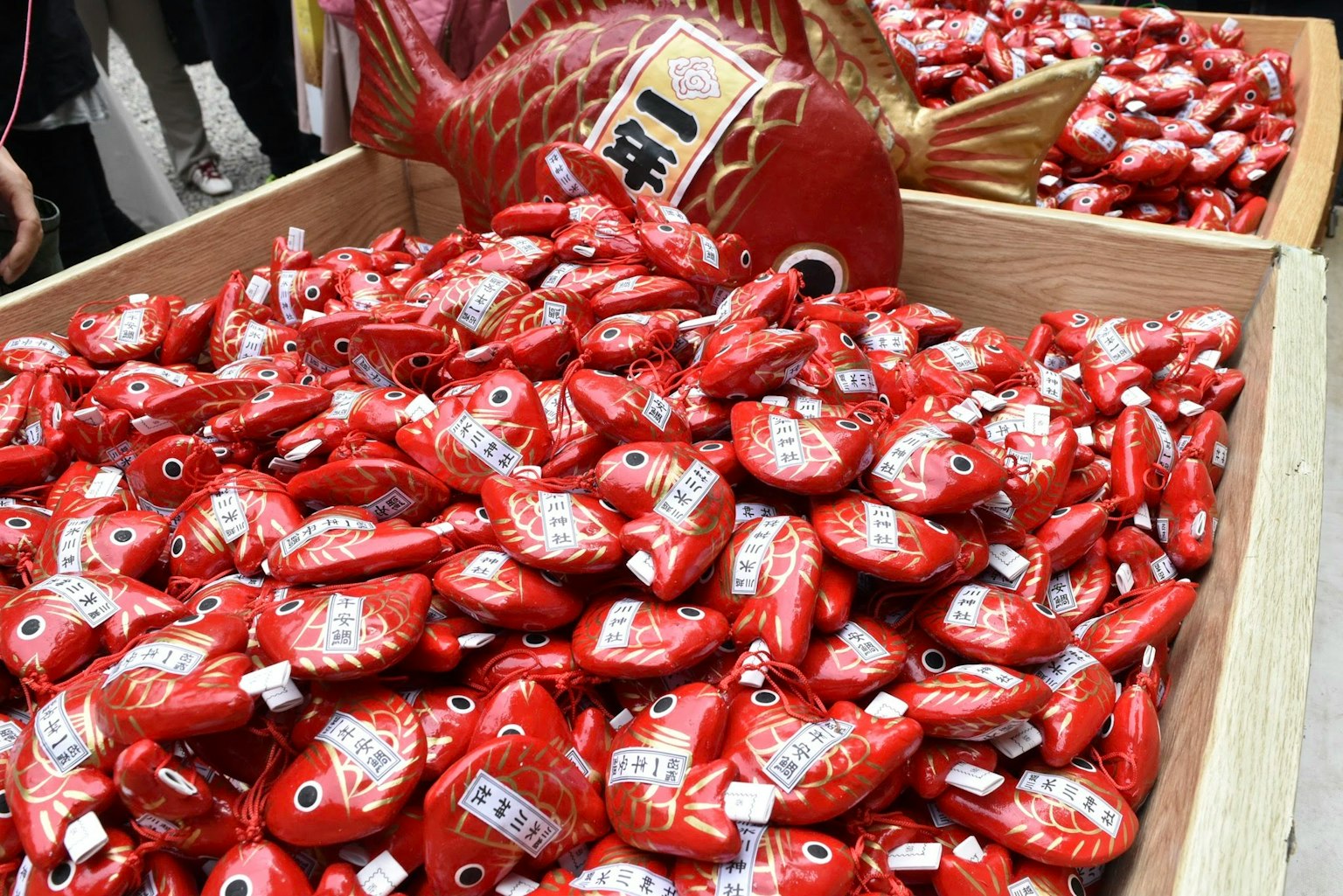 Una grande collezione di amuleti a forma di pesce rosso esposti in scatole di legno