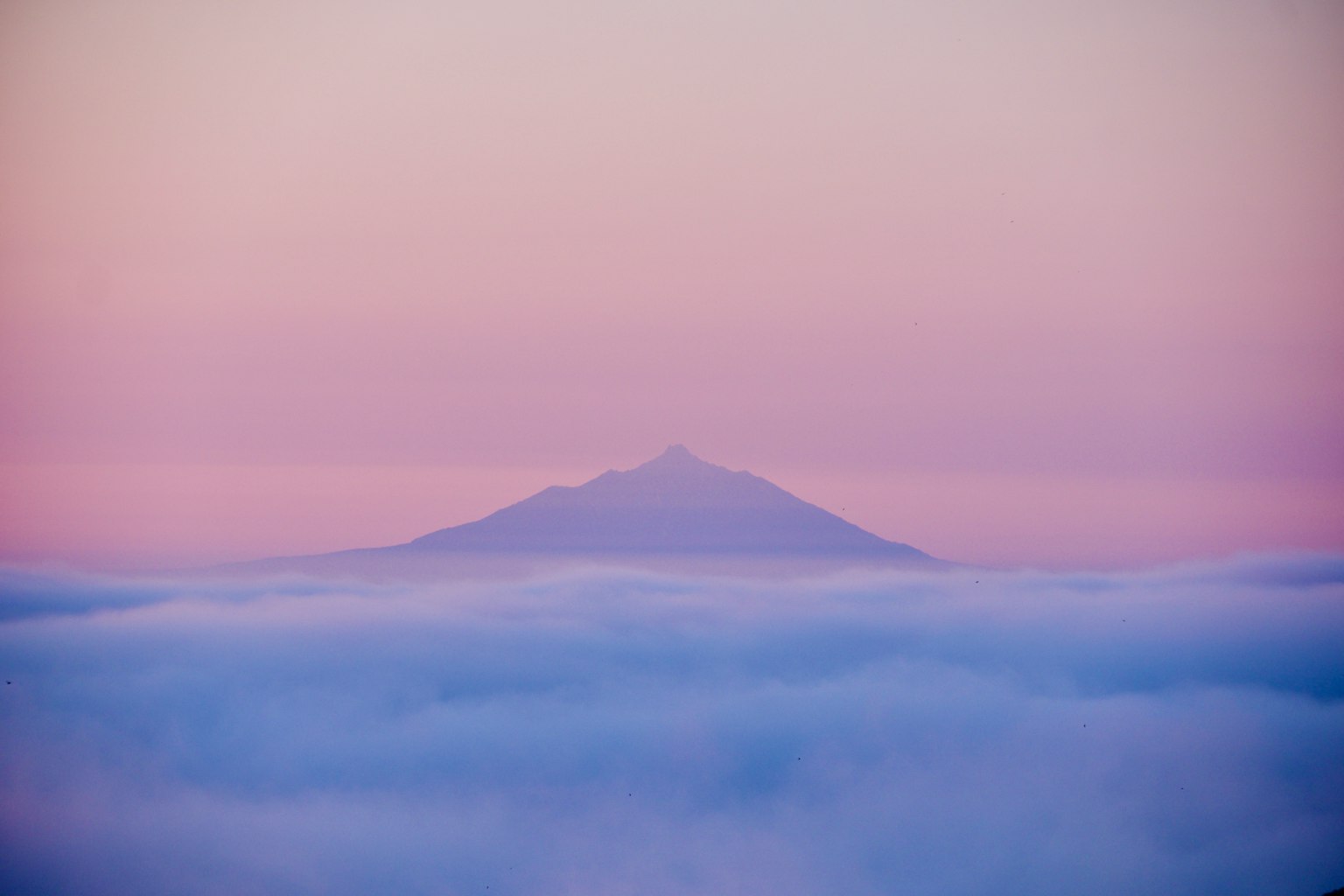Bergsilhouette, die über sanften Wolken bei Dämmerung auftaucht