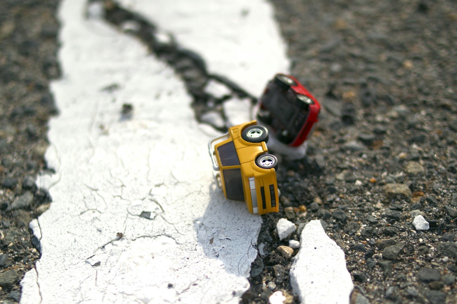 Gelbes Spielzeugauto und rotes Spielzeugauto auf einer weißen Straßenlinie