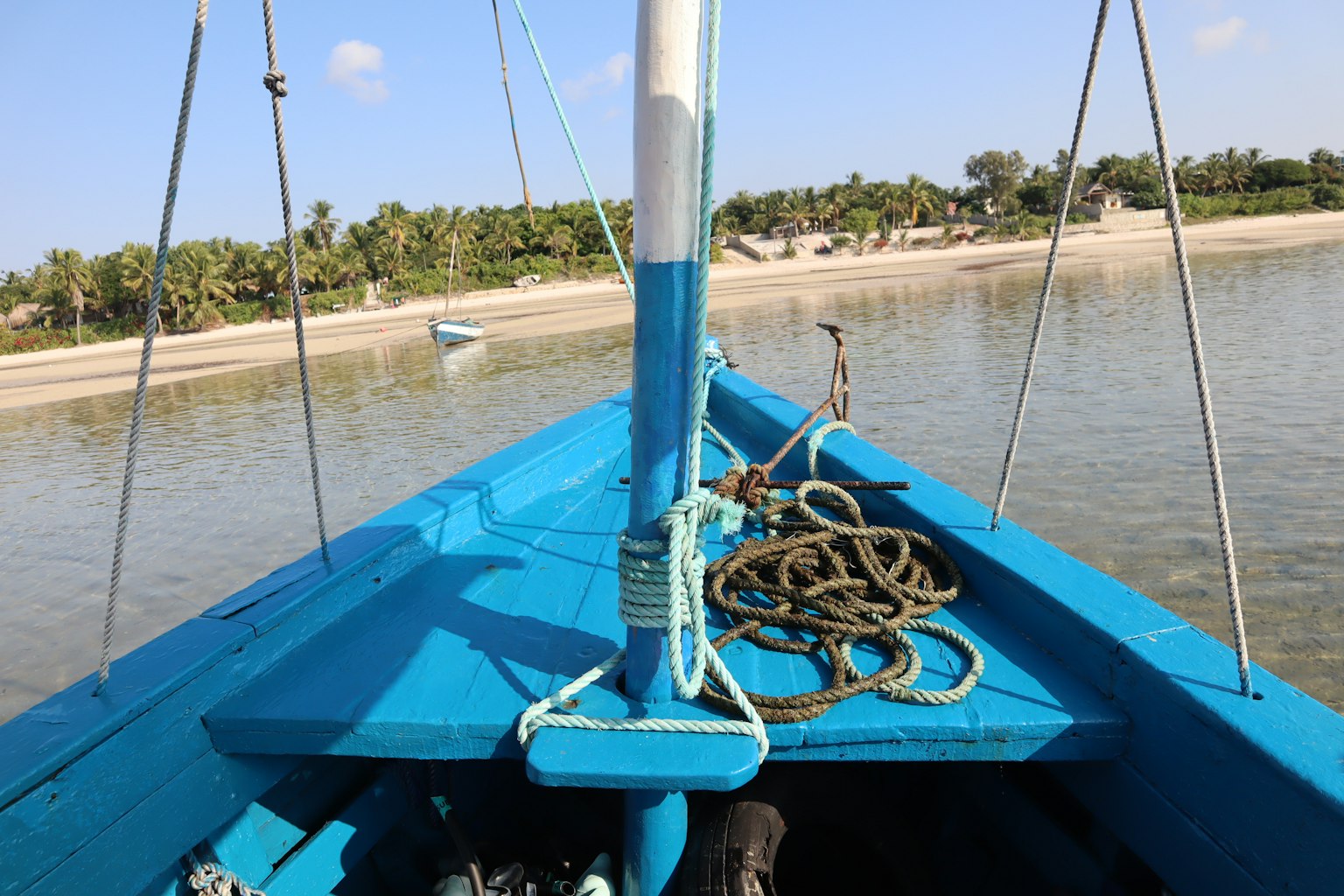 มุมมองจากด้านหน้าของเรือสีน้ำเงินที่มีน้ำสงบและชายหาดในระยะไกล