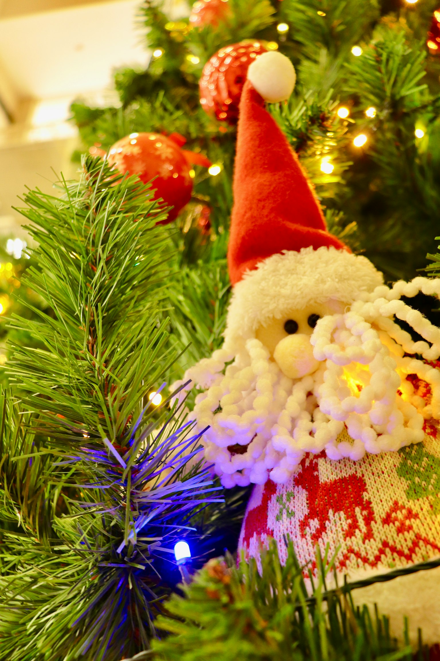 Weihnachtsmann-Dekoration an einem Weihnachtsbaum mit grünen Blättern und Lichtern