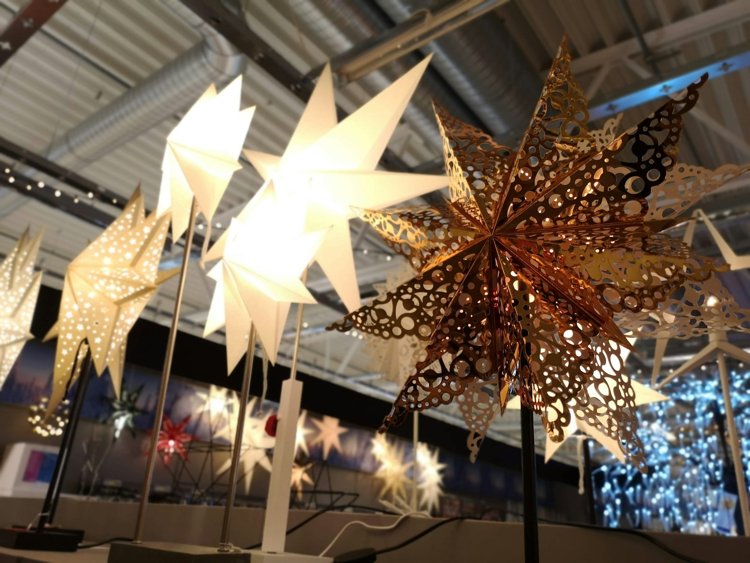 Immagine con lampade a forma di stella bianche e una lampada a stella dorata decorativa
