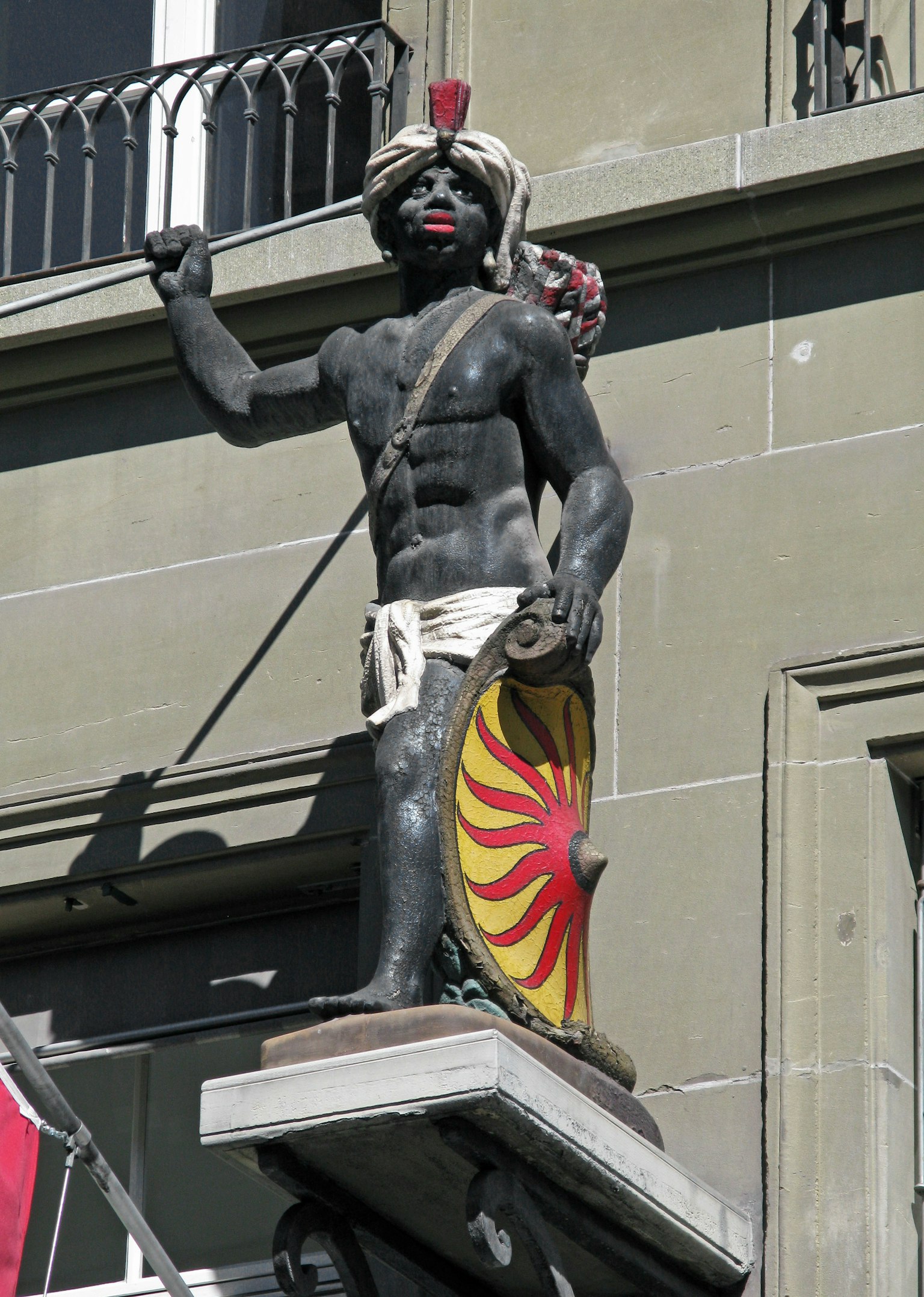 Statue d'un guerrier à la peau noire tenant un bouclier sur la façade d'un bâtiment