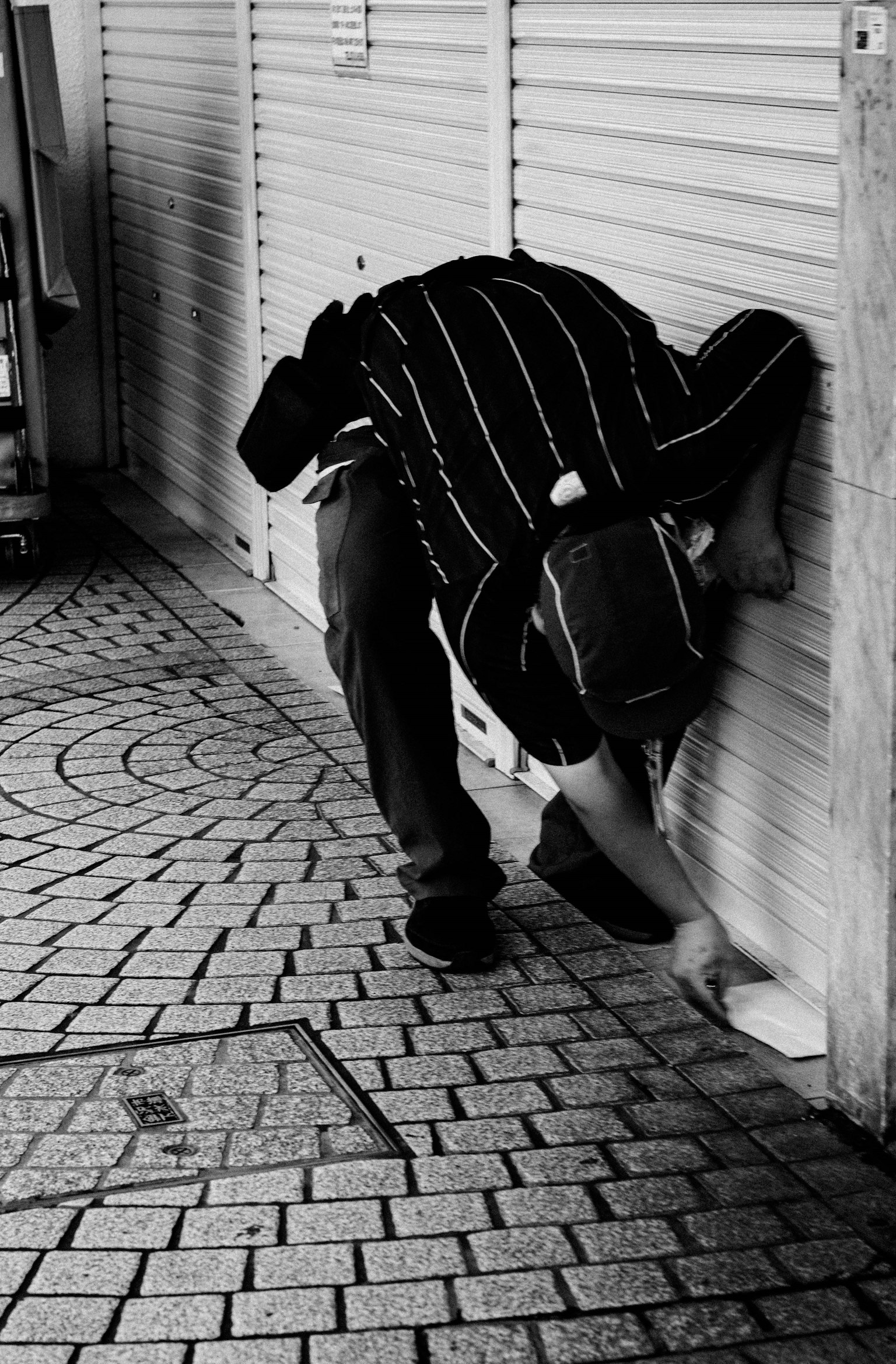 Foto en blanco y negro de una persona inclinándose cerca de una pared