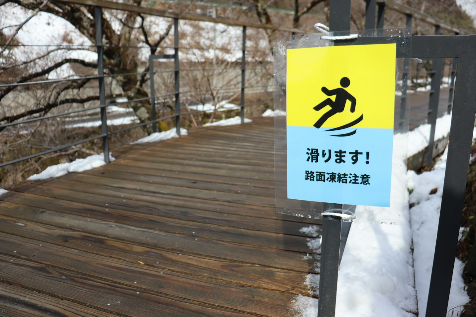 雪覆蓋的木棧道上的滑倒警告標誌