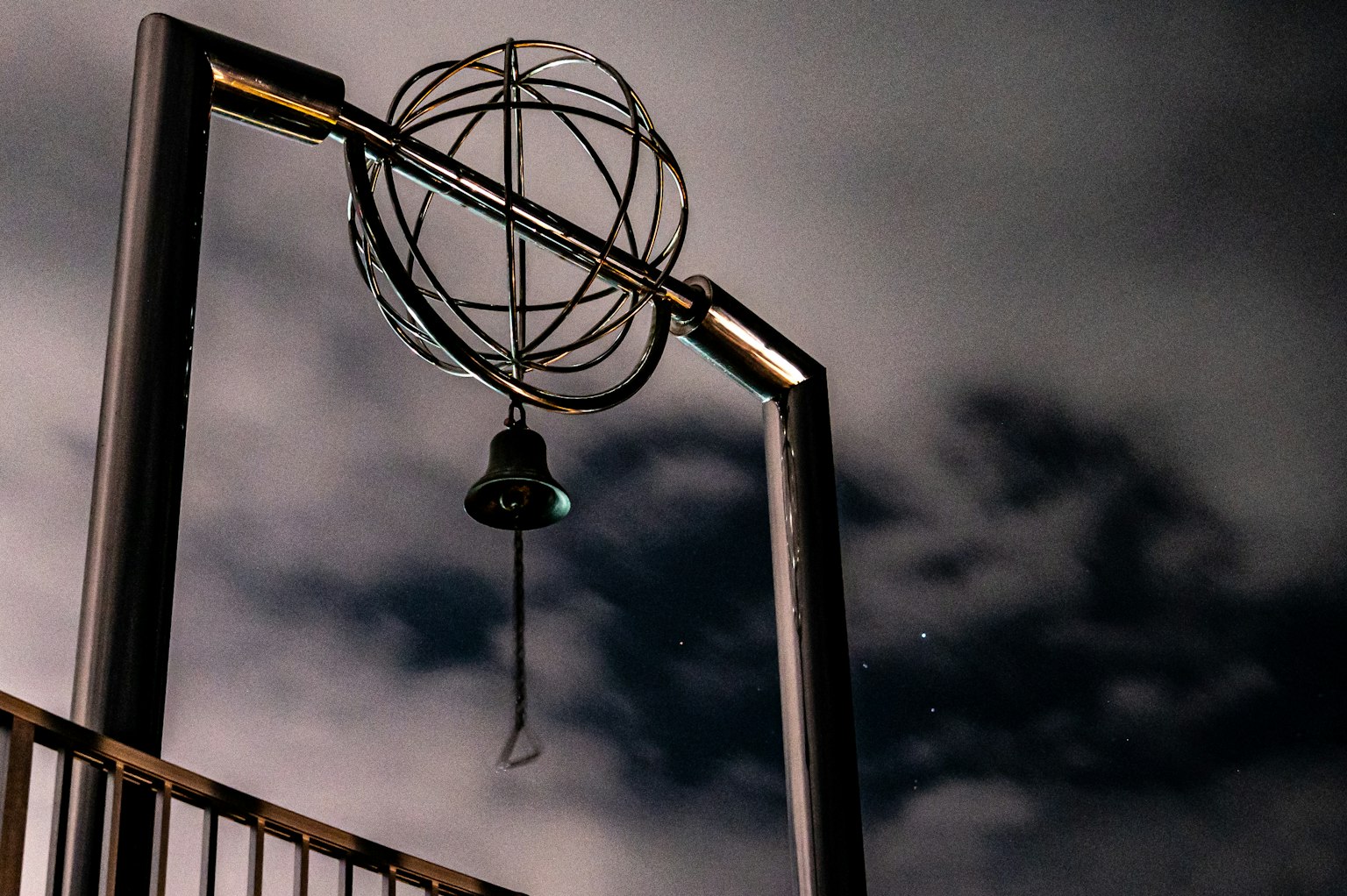 Foto de una estructura con un globo plateado y una campana colgante