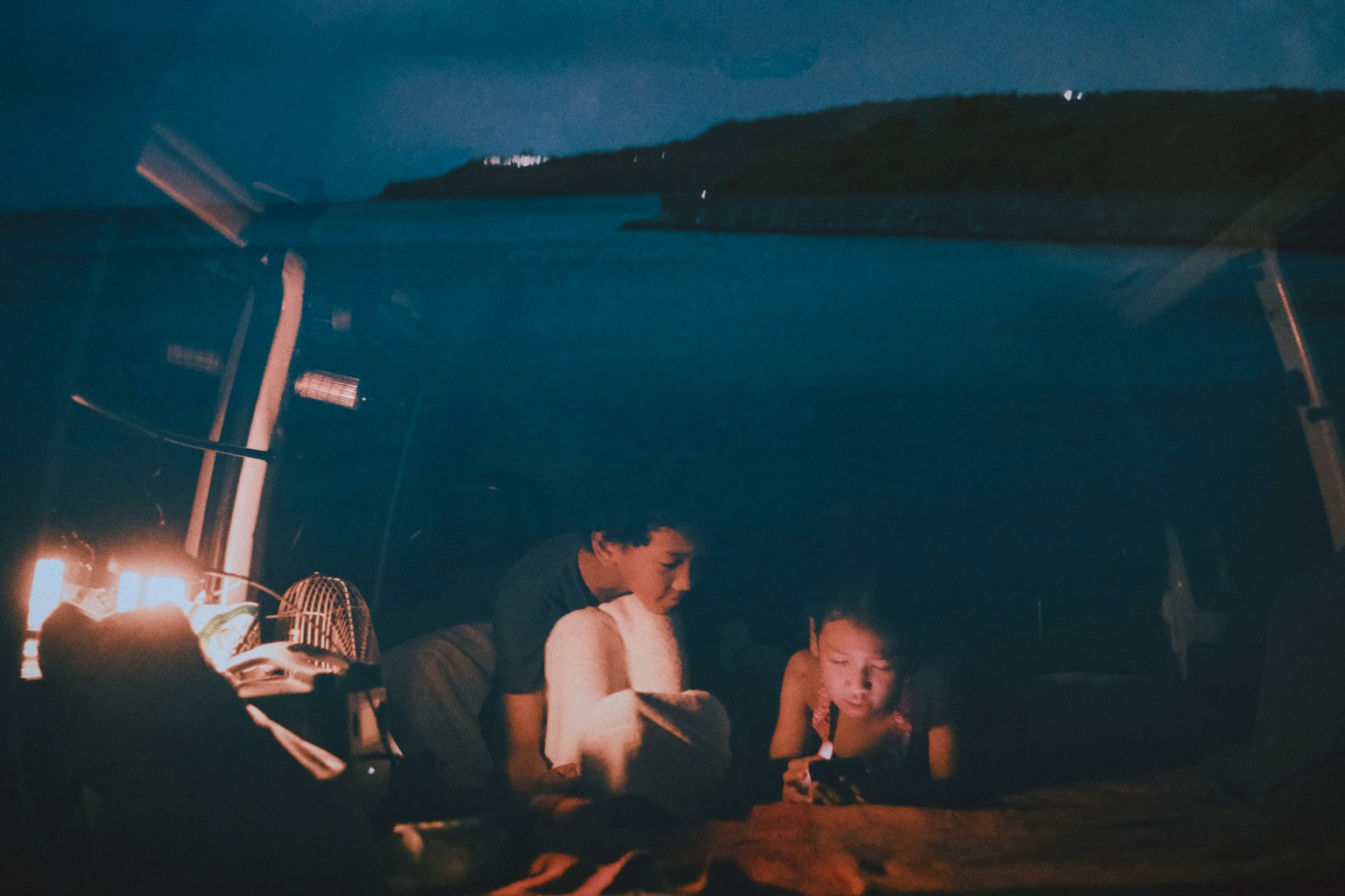 Silhouette of two young people relaxing inside a vehicle at night