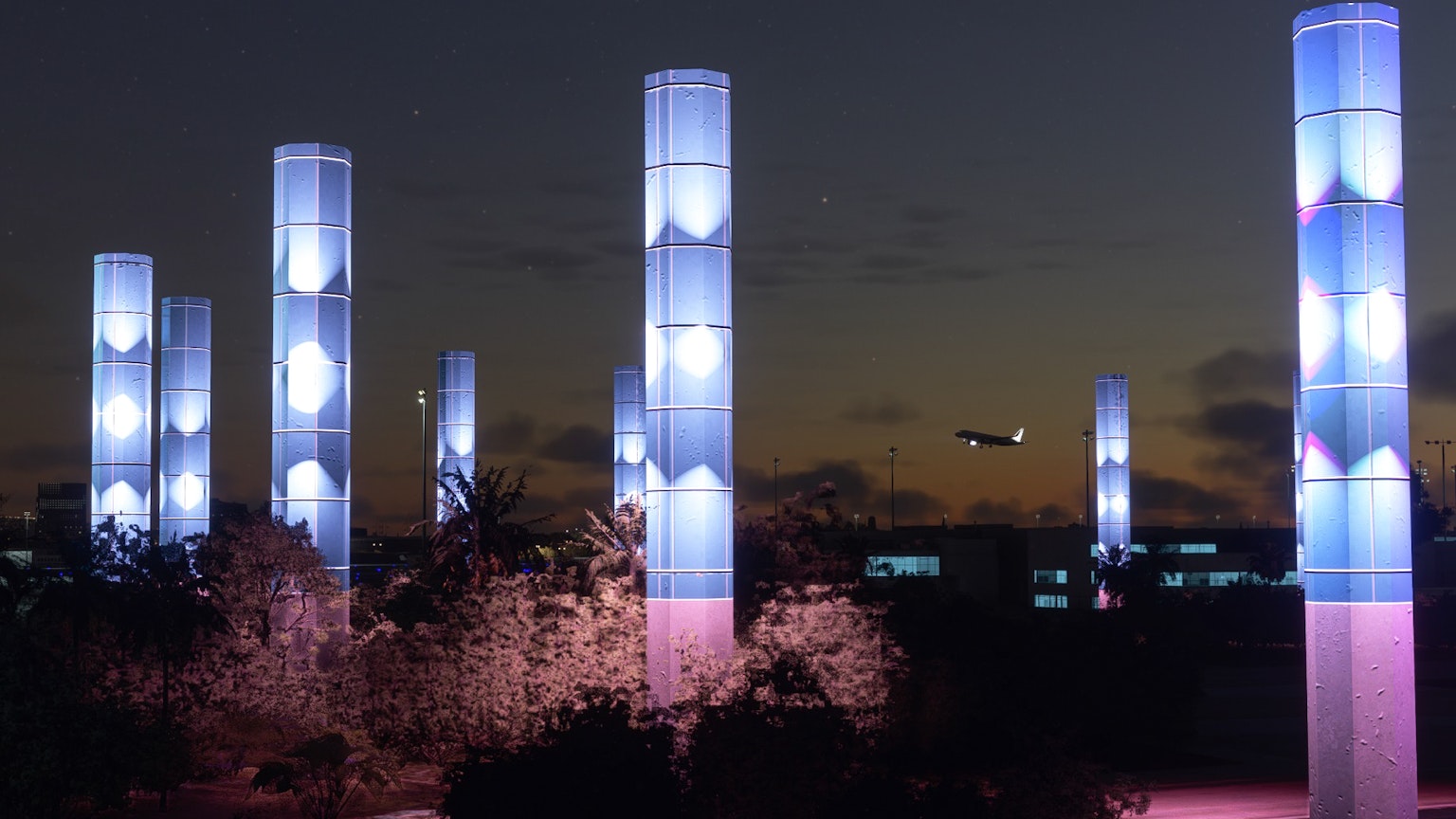 Colonnes illuminées dans un ciel nocturne avec un avion en arrière-plan
