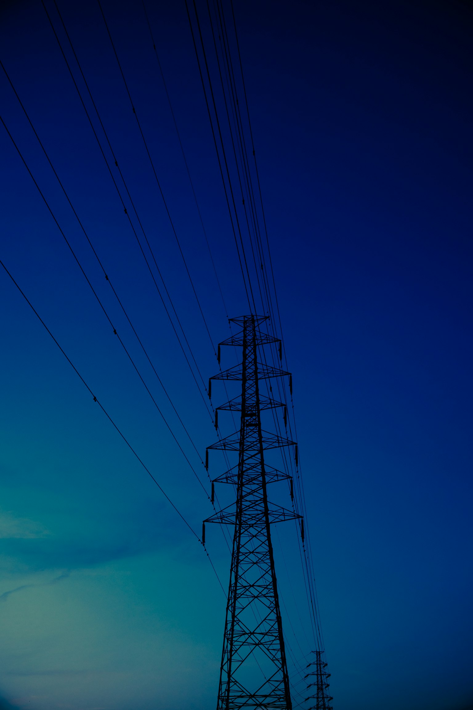 Torre eléctrica en silueta contra un cielo azul profundo