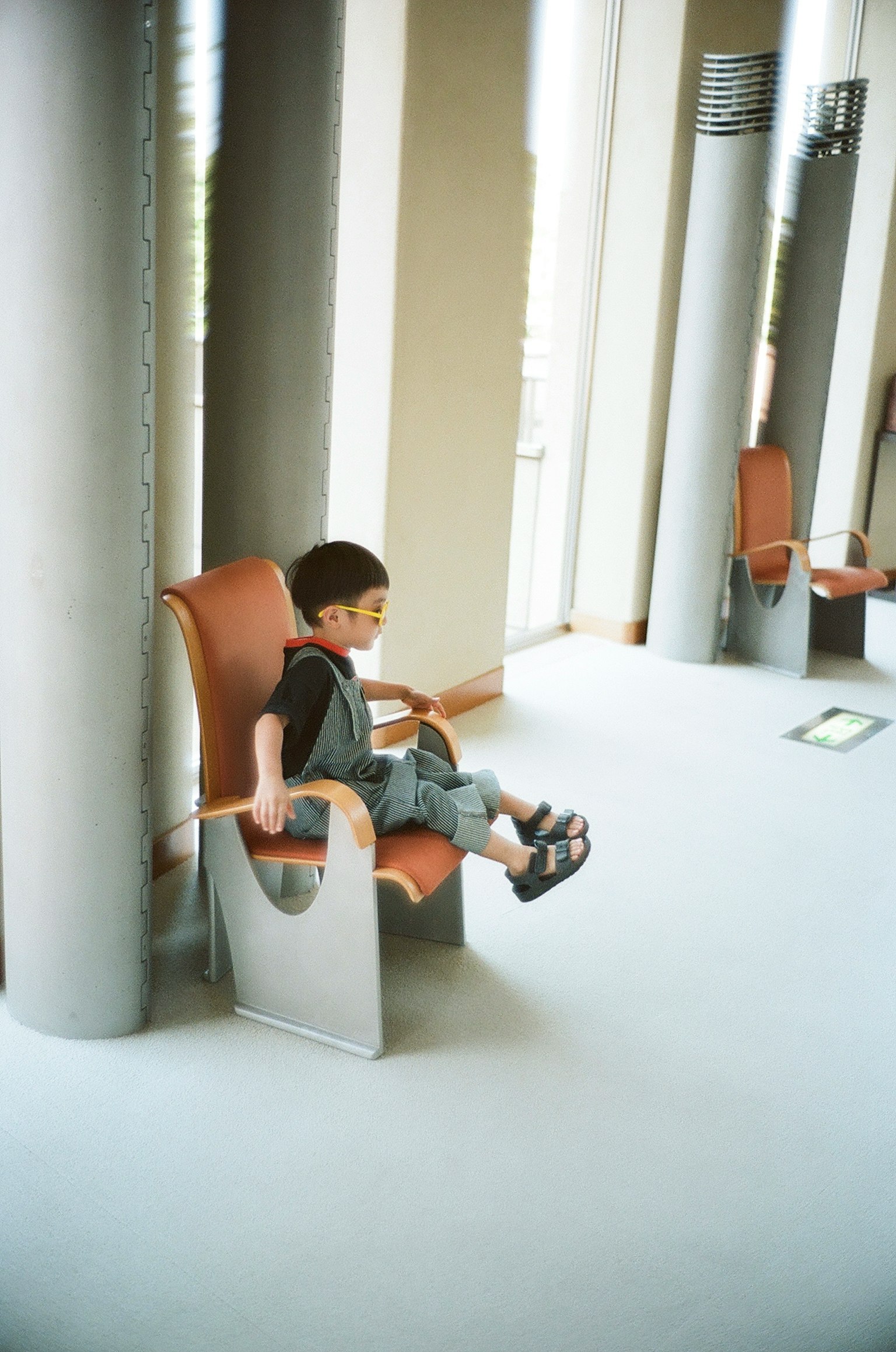 Un niño sentado en una silla moderna en un entorno interior