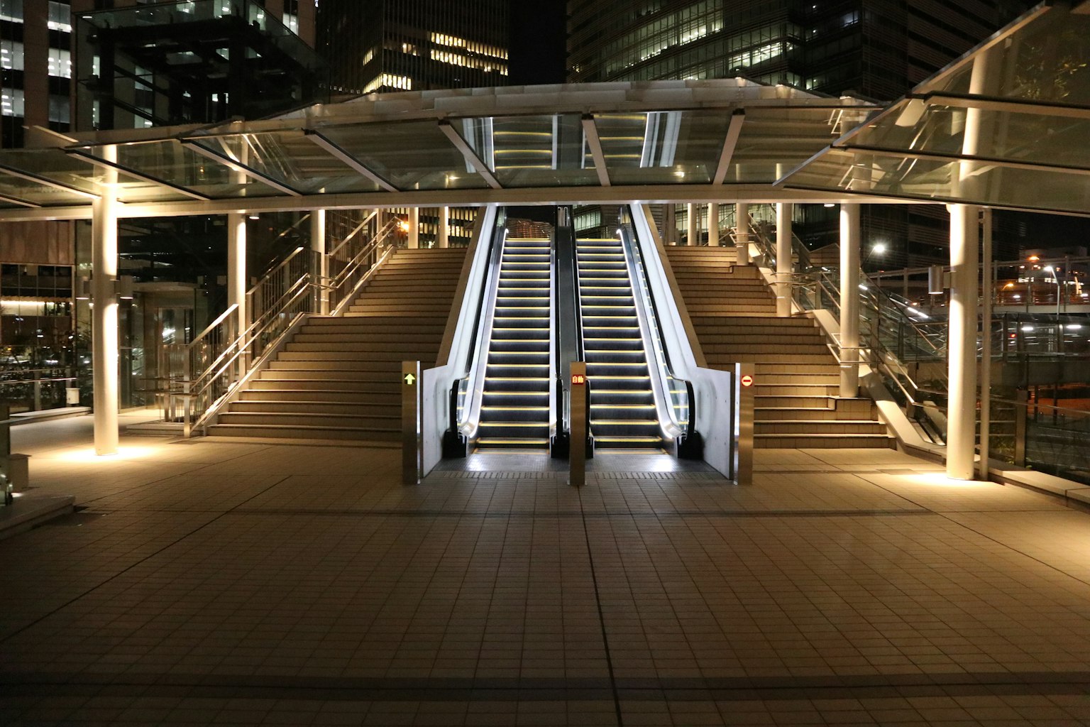 Escalera iluminada y pasarela en un paisaje urbano nocturno