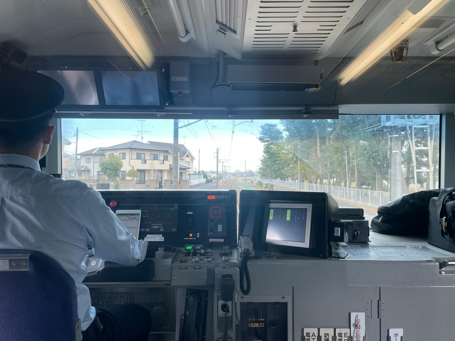 Train conductor in the cockpit looking ahead with visible controls and monitors
