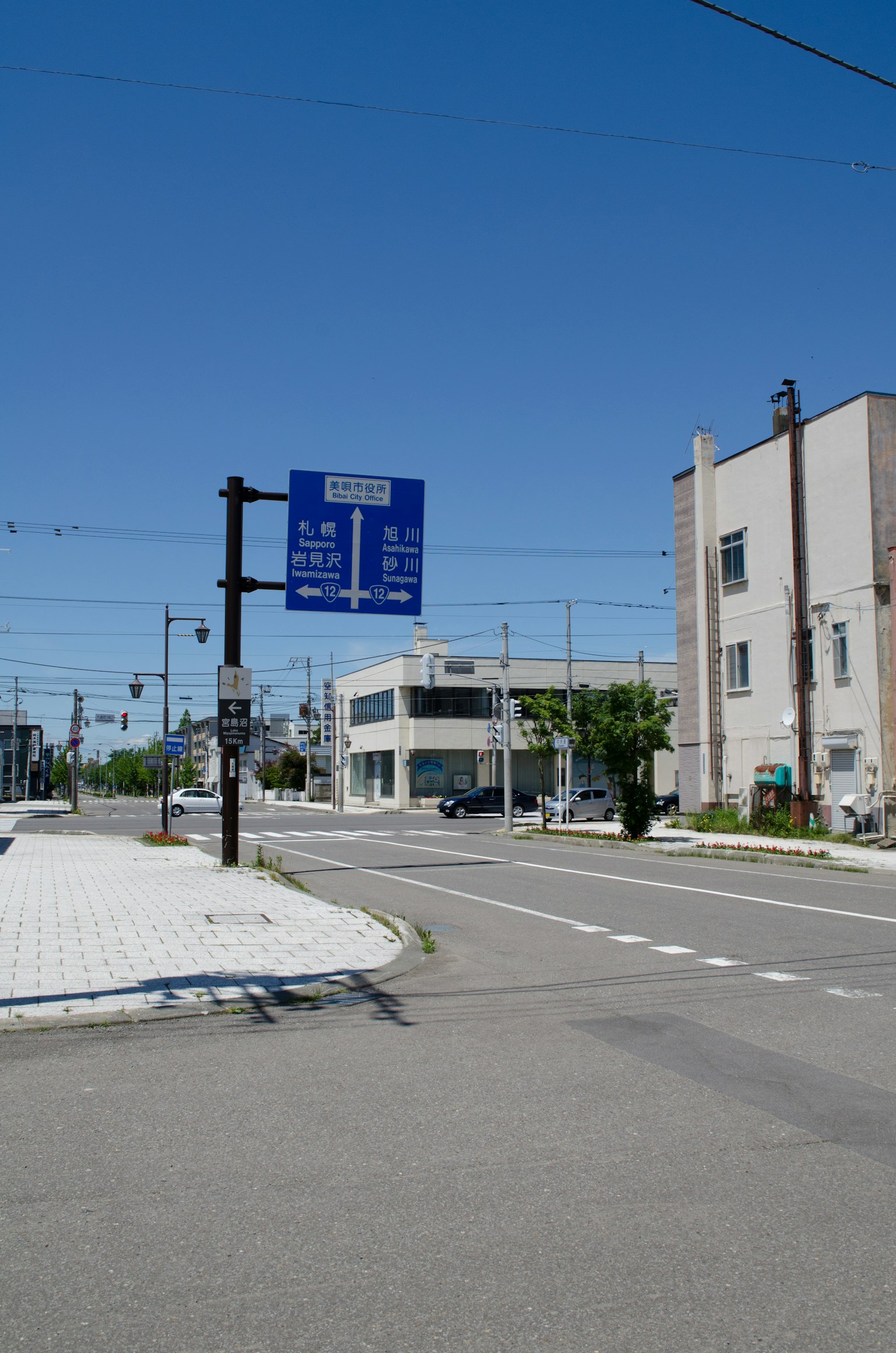 Escena de intersección con una señal de tráfico y edificios cercanos bajo un cielo azul claro
