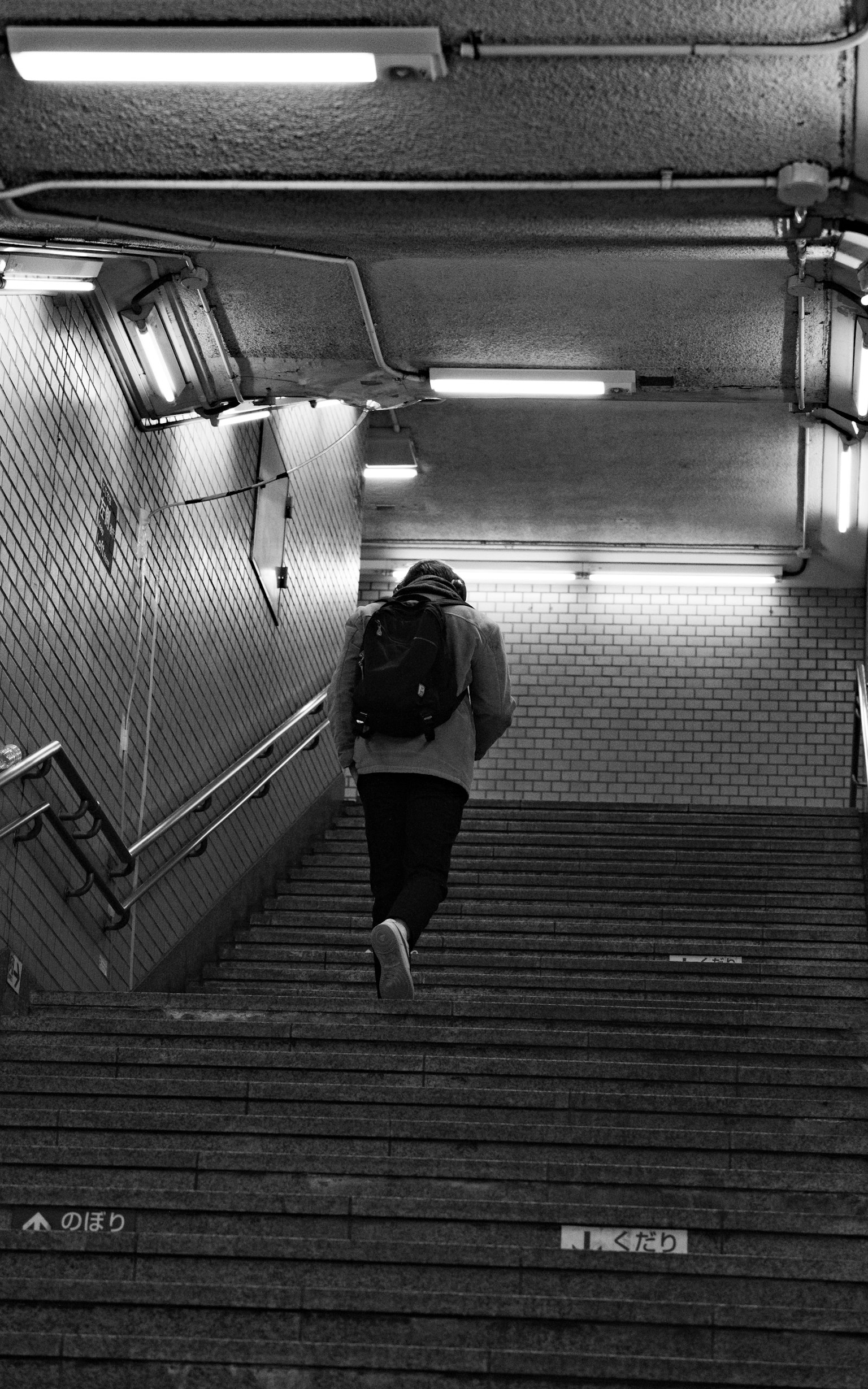 Personne montant des escaliers en noir et blanc lumières vives dans une station de métro
