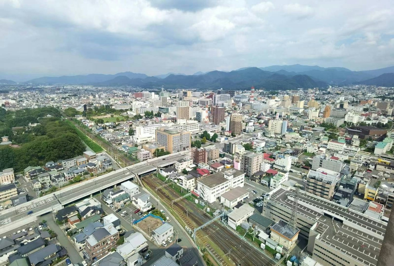 日本城市的航拍視圖，背景有建築和山脈