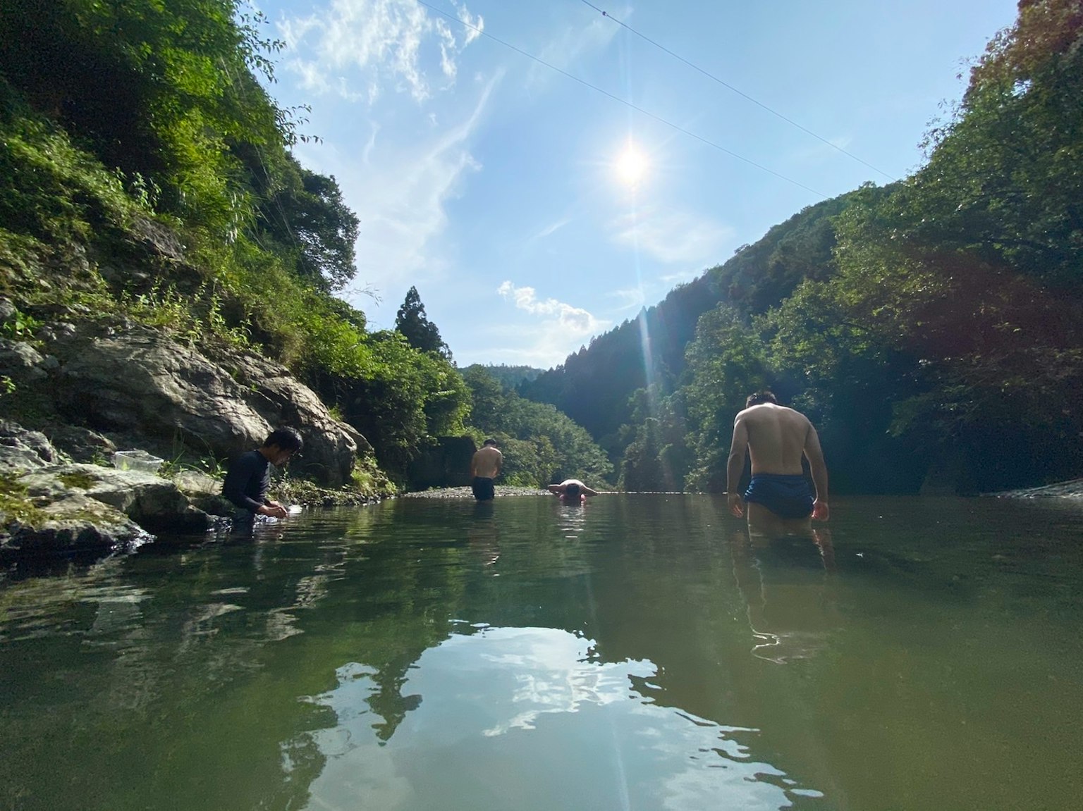 Menschen genießen einen Fluss unter einem hellblauen Himmel und umgebender Vegetation