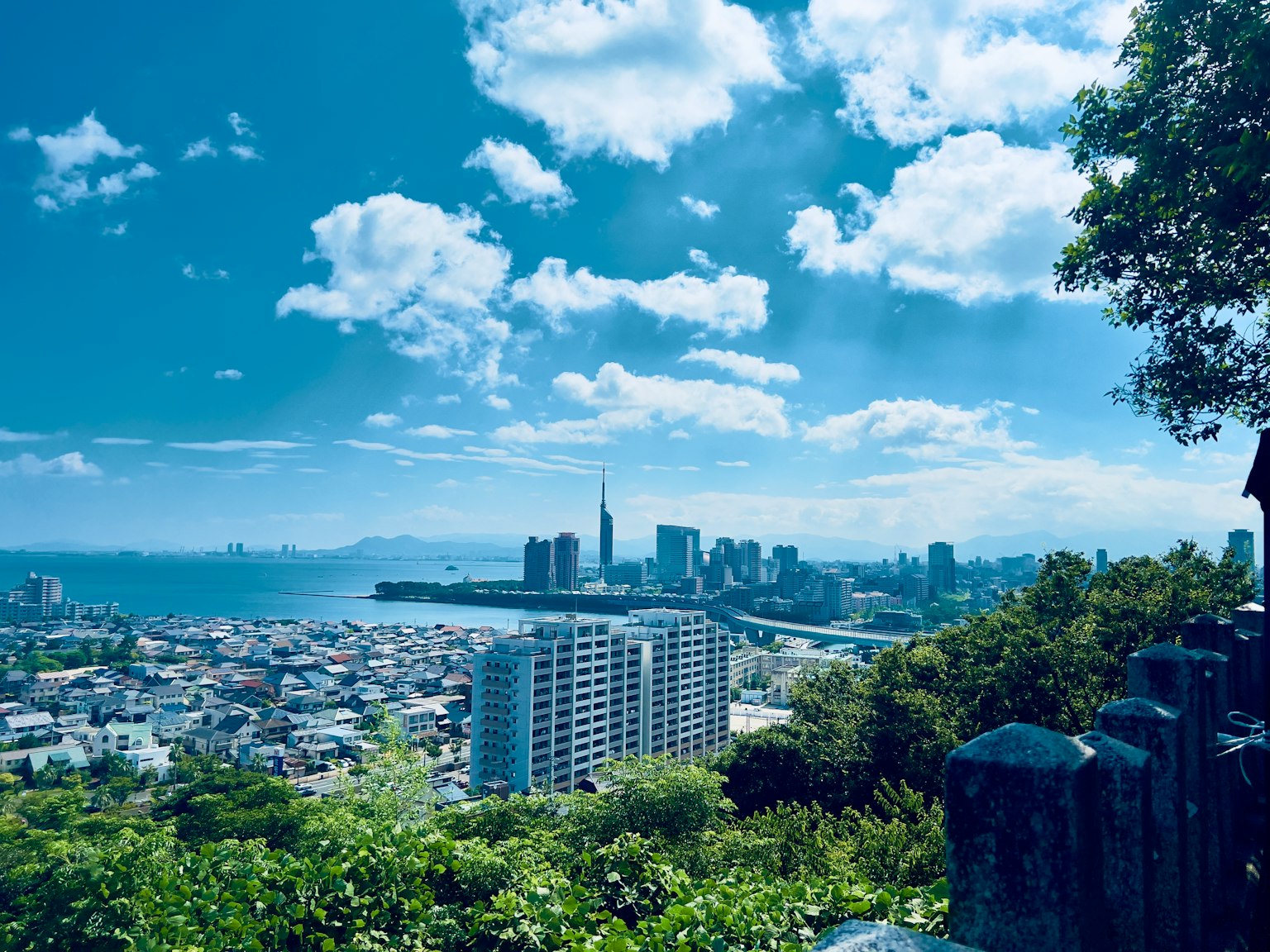 วิวพาโนรามาของเมืองที่มีท้องฟ้าสีฟ้าและเมฆมองจากยอดเขาที่มีอาคารและทะเล