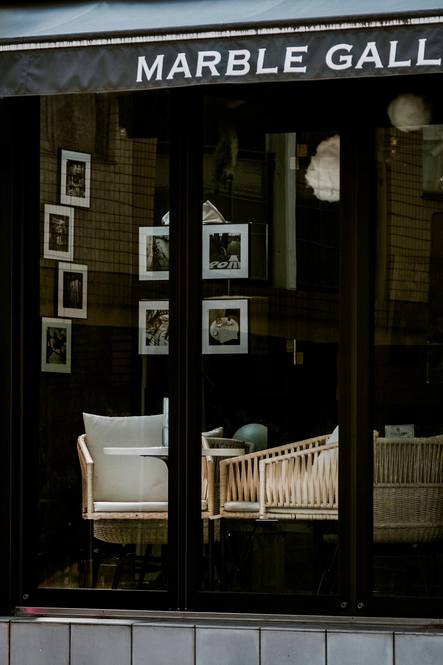 Vue extérieure d'un café avec des chaises blanches et des photos encadrées dans la fenêtre