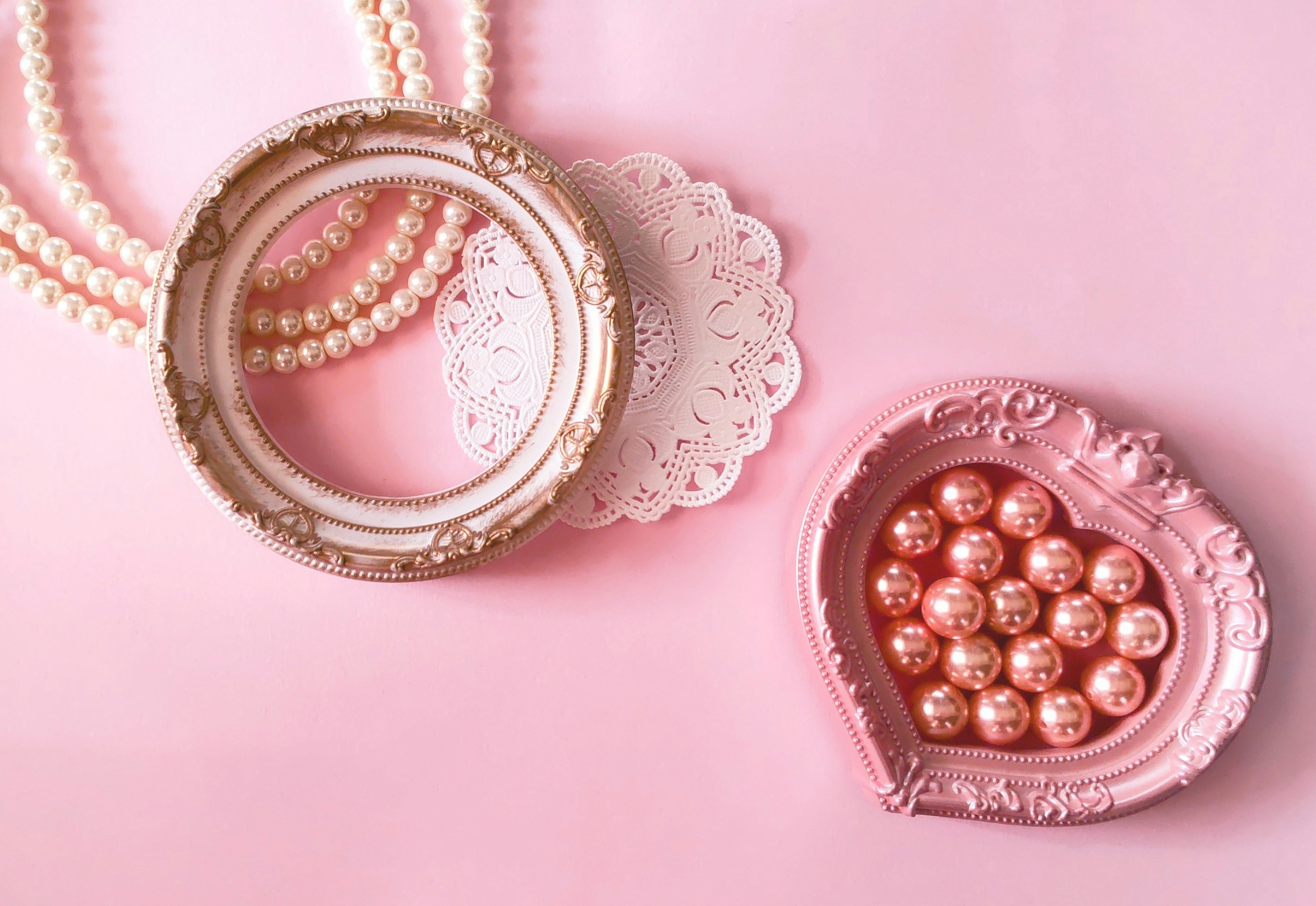 Valentine-style heart-shaped frames with pearls and lace paper on a pink background