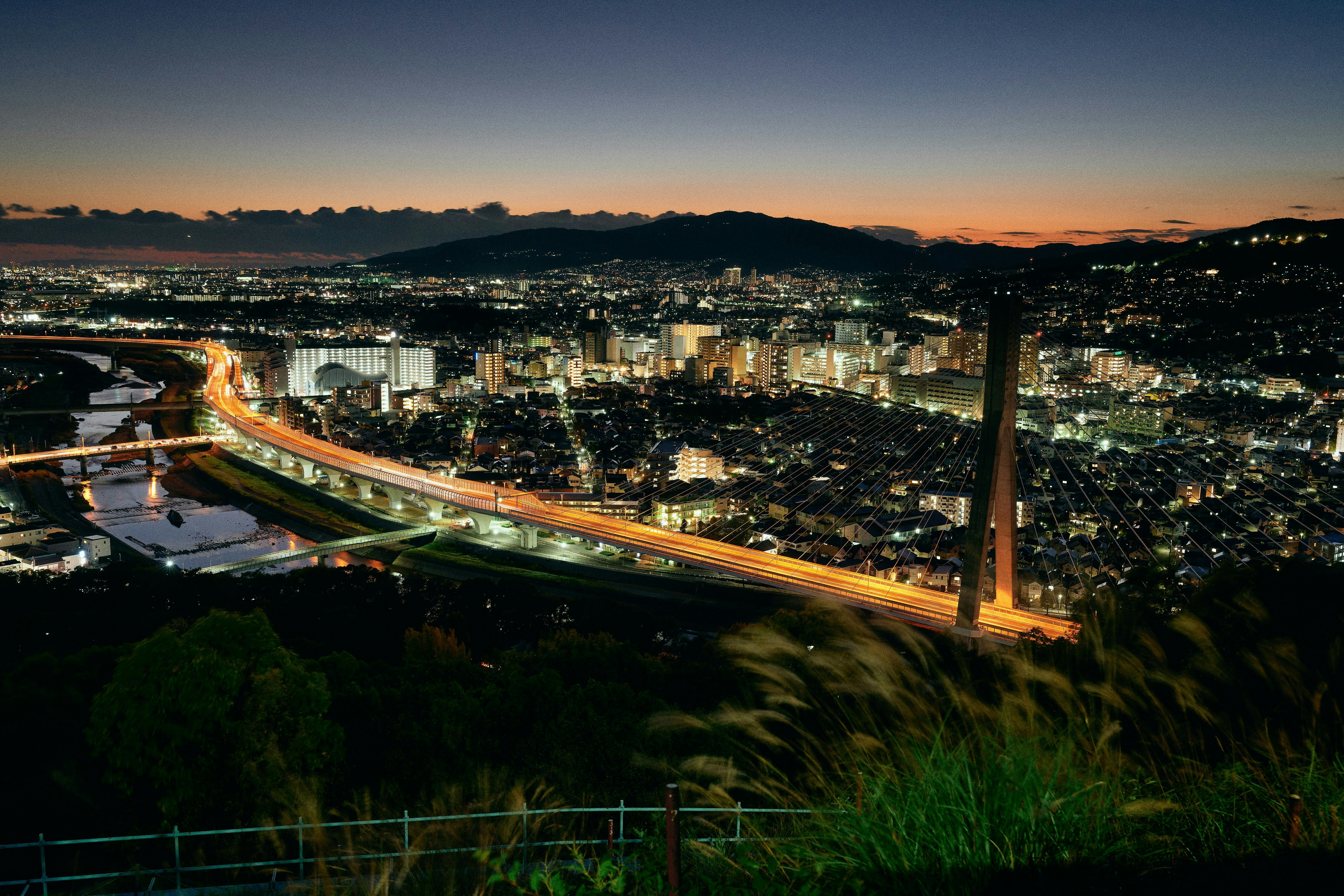 夕暮れの夜景を見下ろす高架道路と街並み